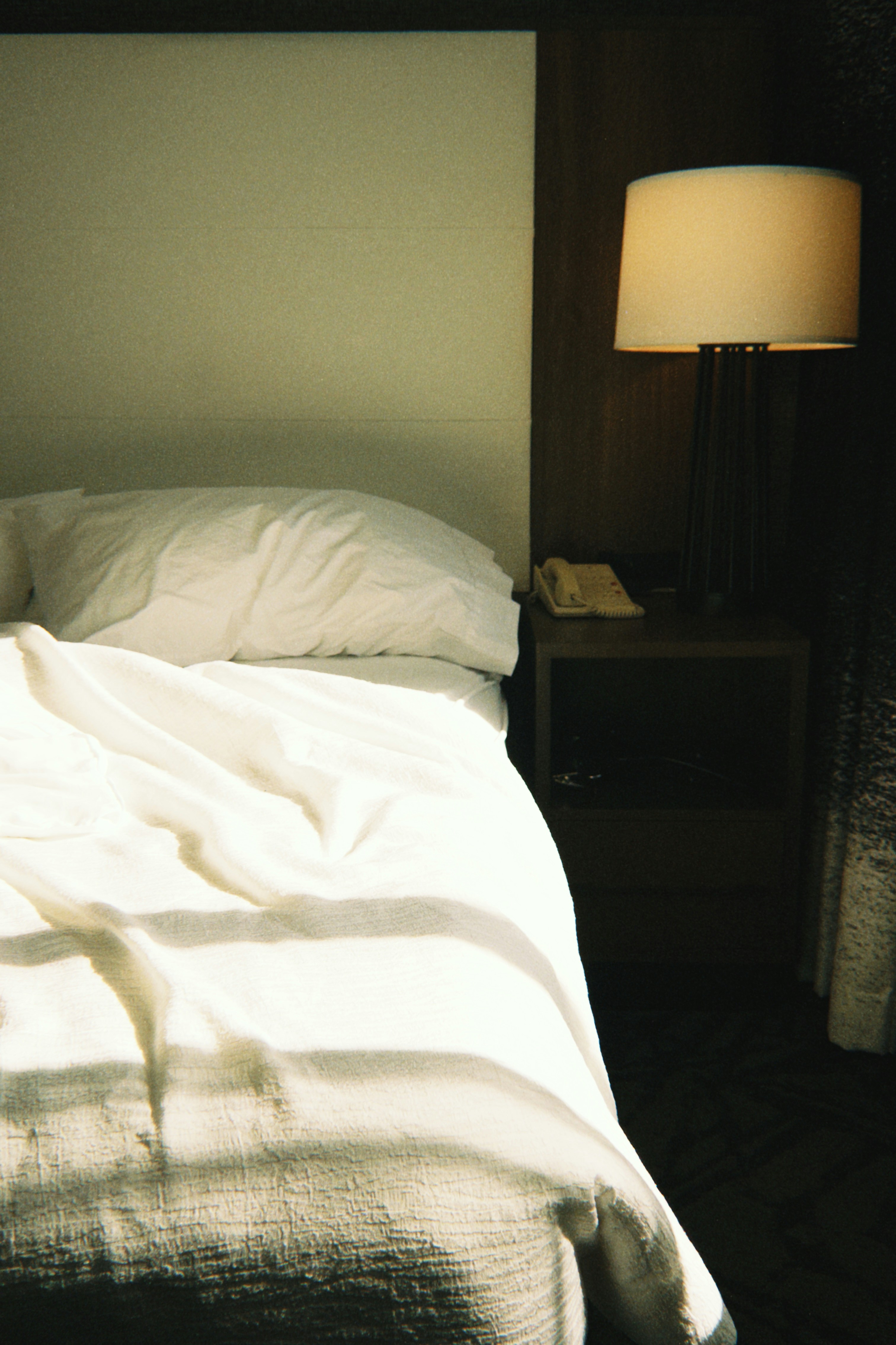 Unmade bed with sunlight streaming across the sheets.