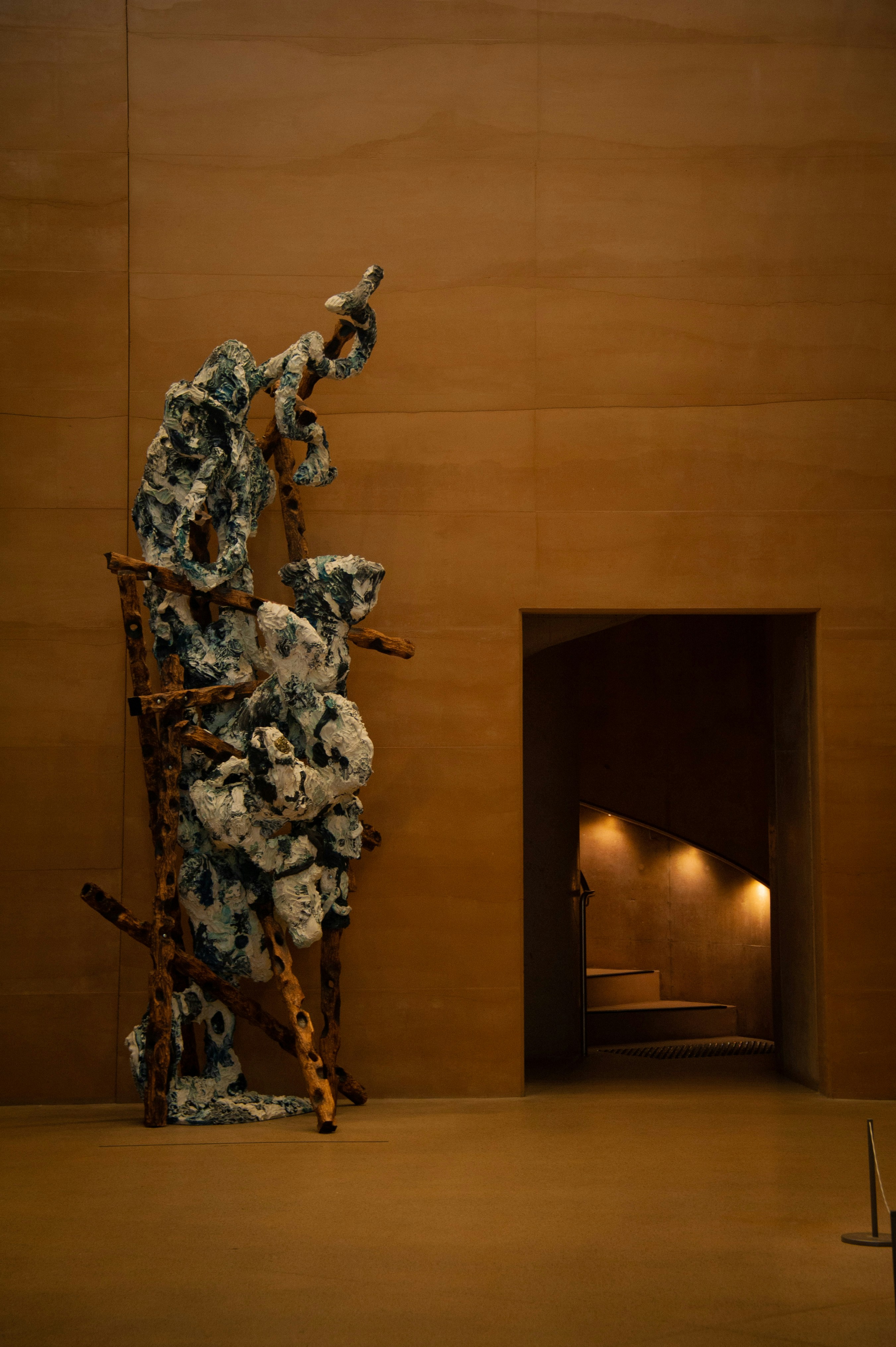 Abstract sculpture with wooden elements against a textured wall