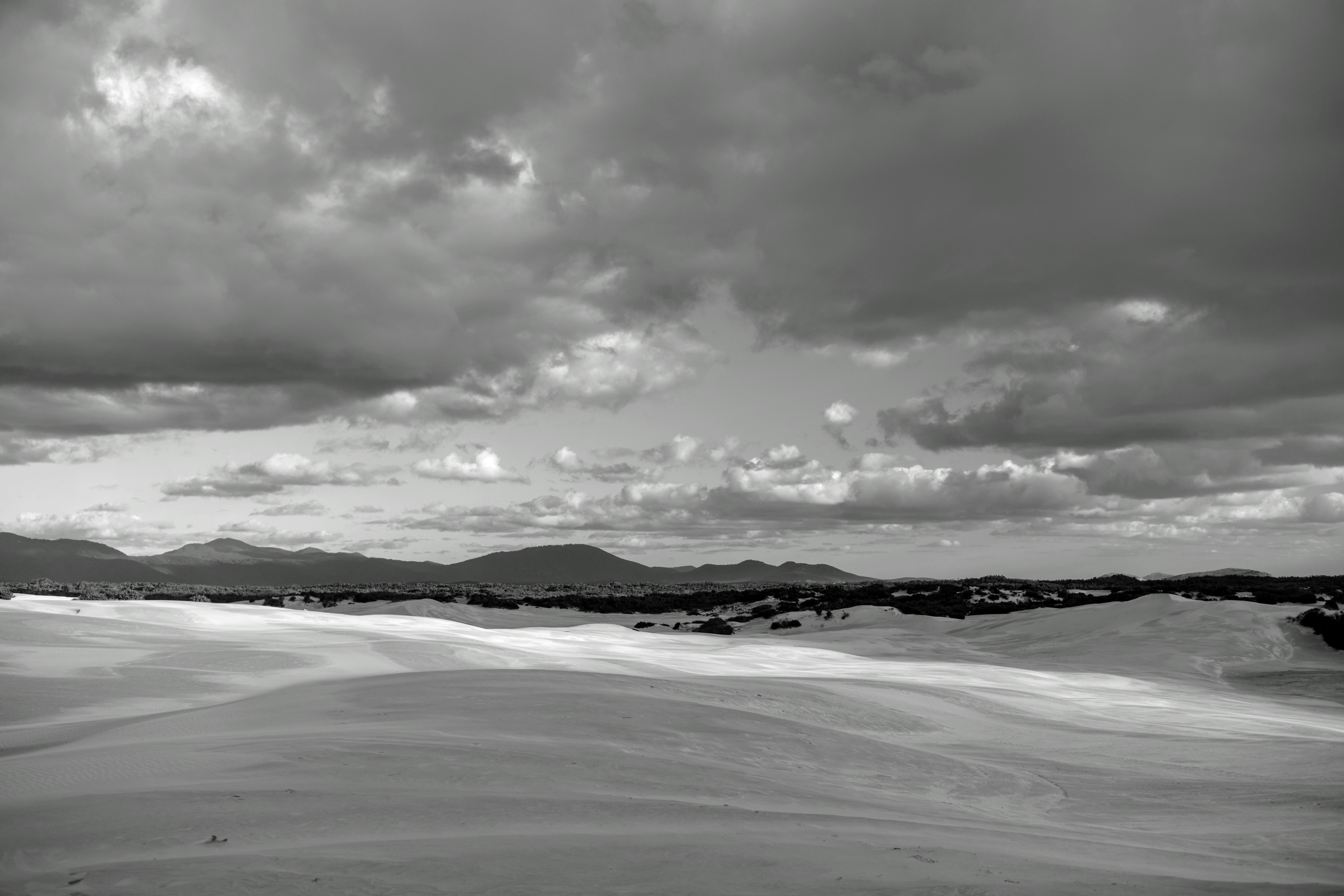 Nuvole drammatiche sopra dune di sabbia ondulate