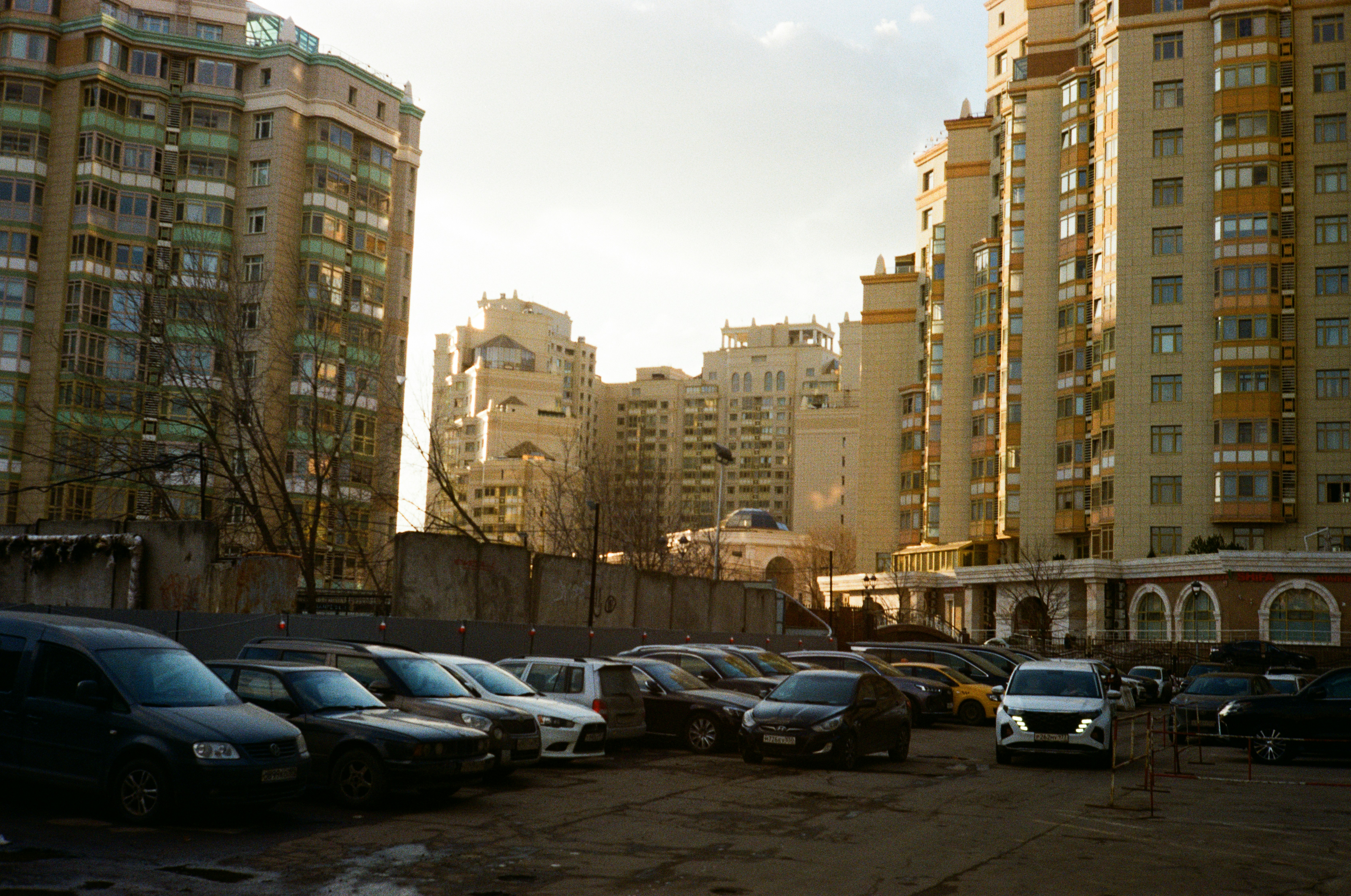 Carros estacionados em um estacionamento com prédios de apartamentos atrás.