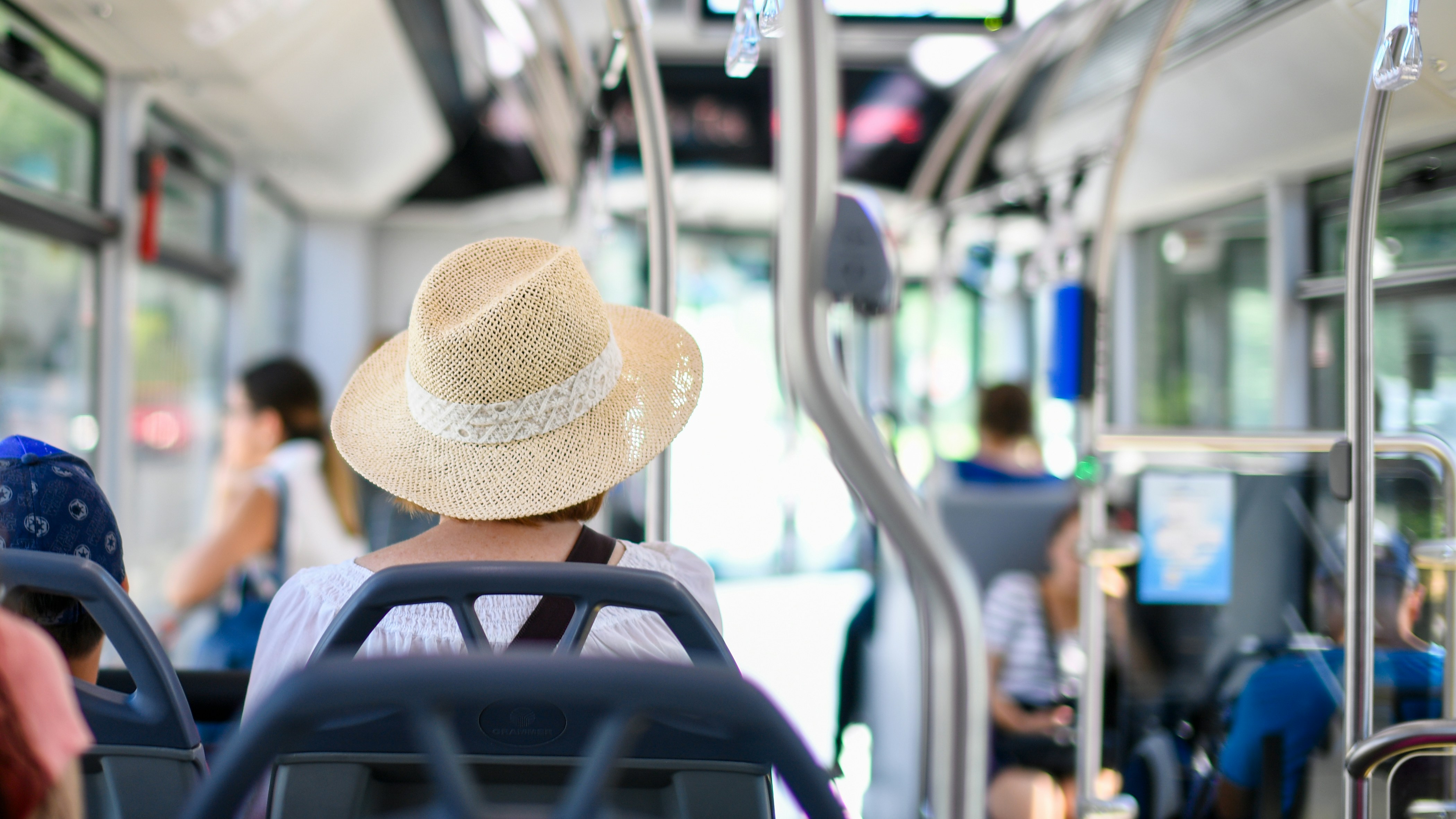 Tourist woman in a straw hat traveling on a public bus during a sunny summer day in Croatia.
