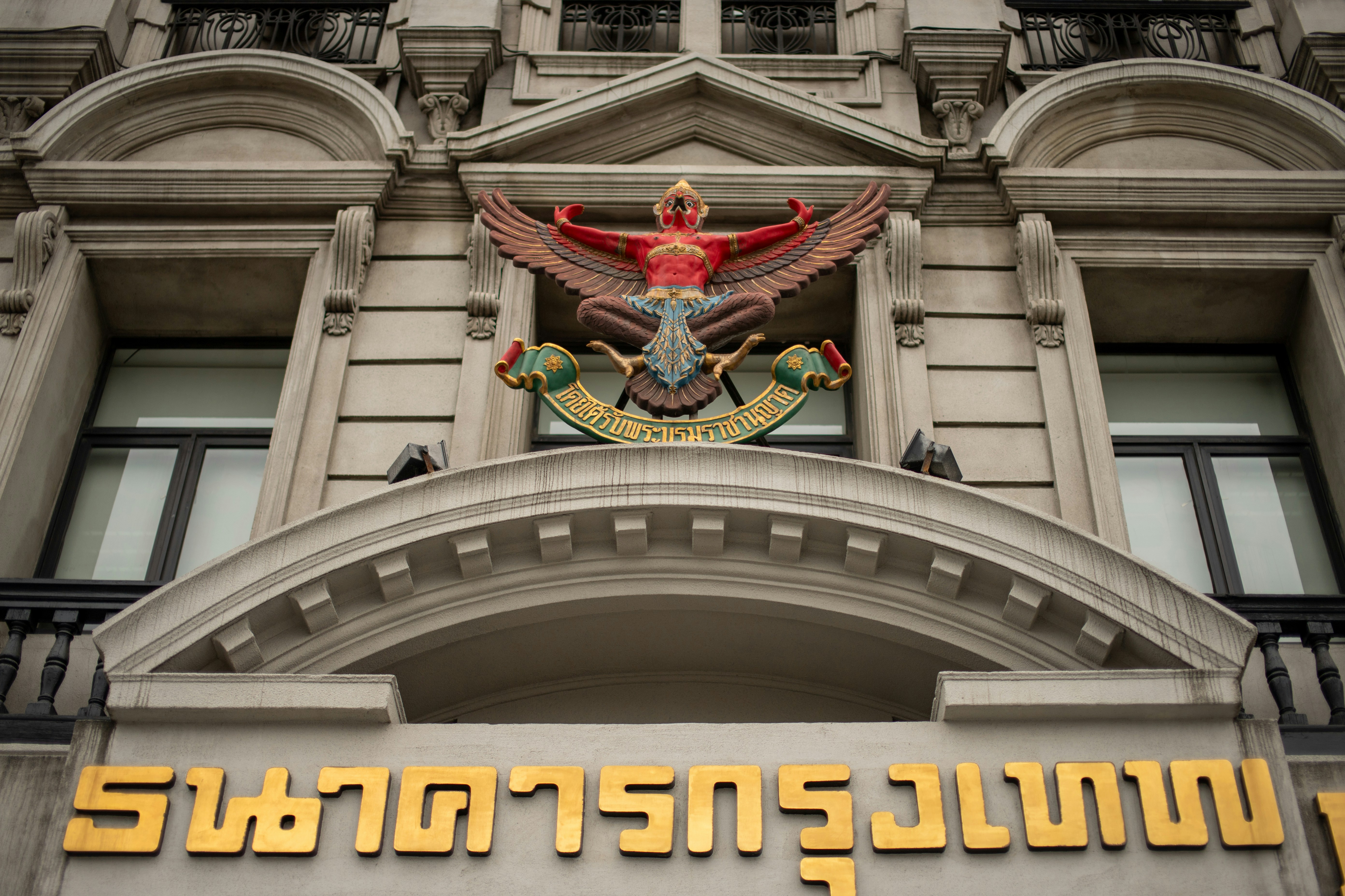 Ornate building facade with golden thai script and emblem.