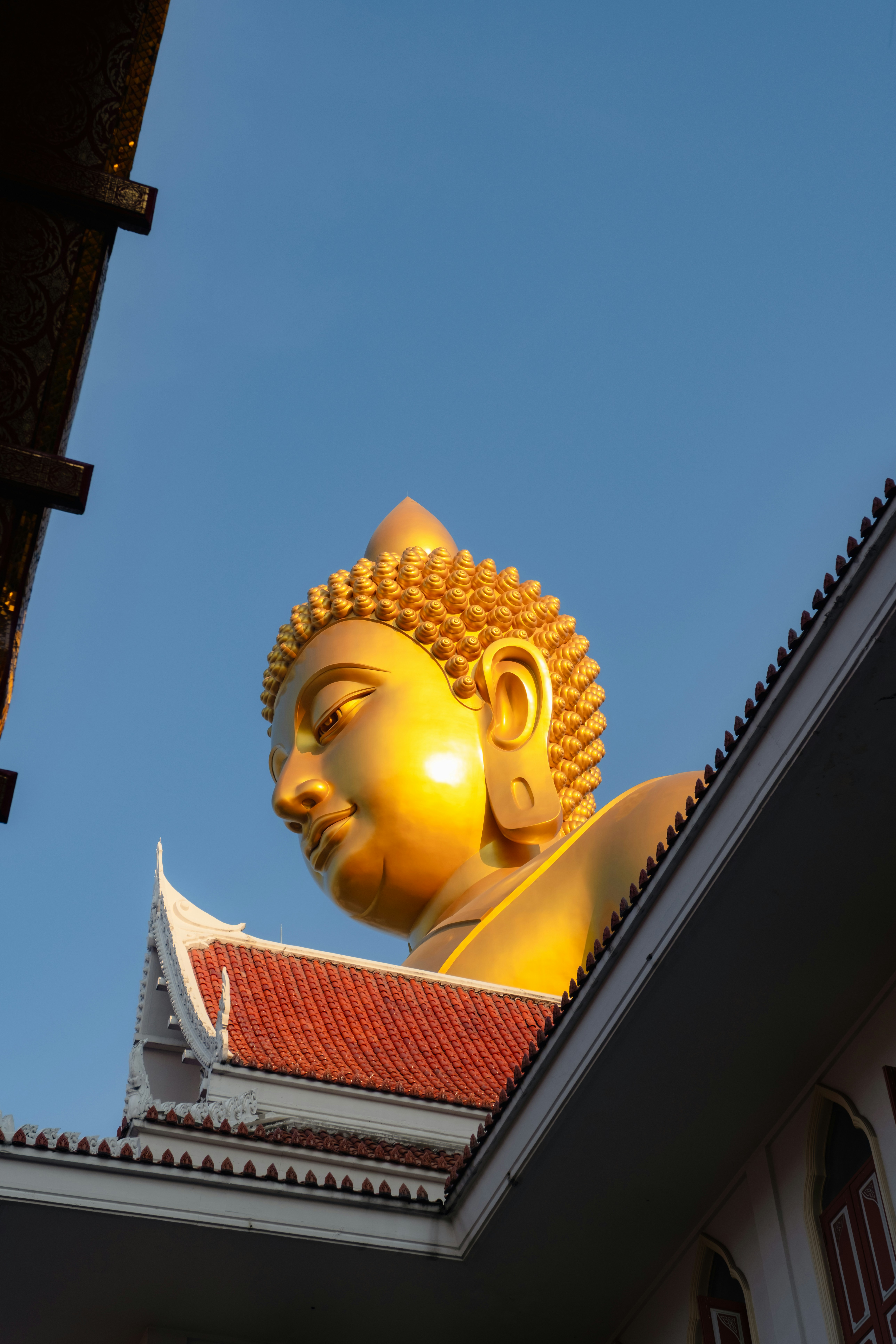 Golden buddha statue against a clear blue sky.