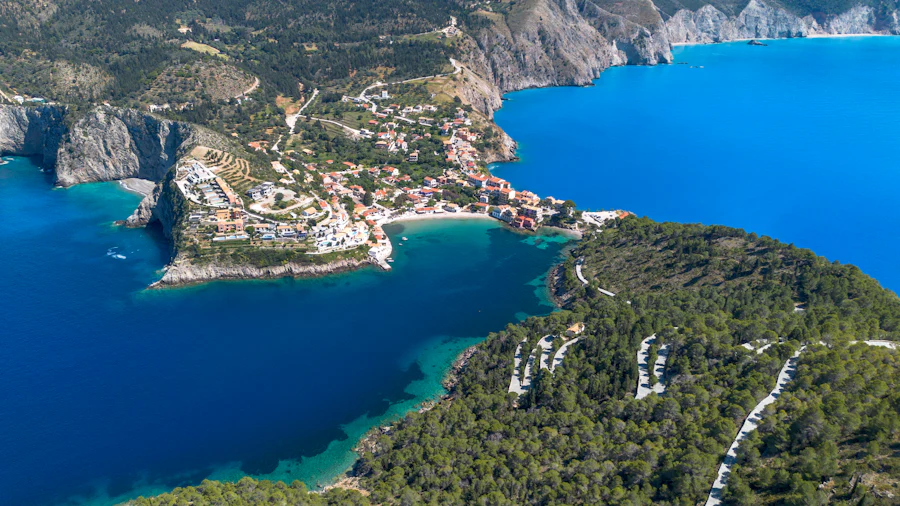 Aerial view of a deep blue and green bay with a small settlement on the shoreline.