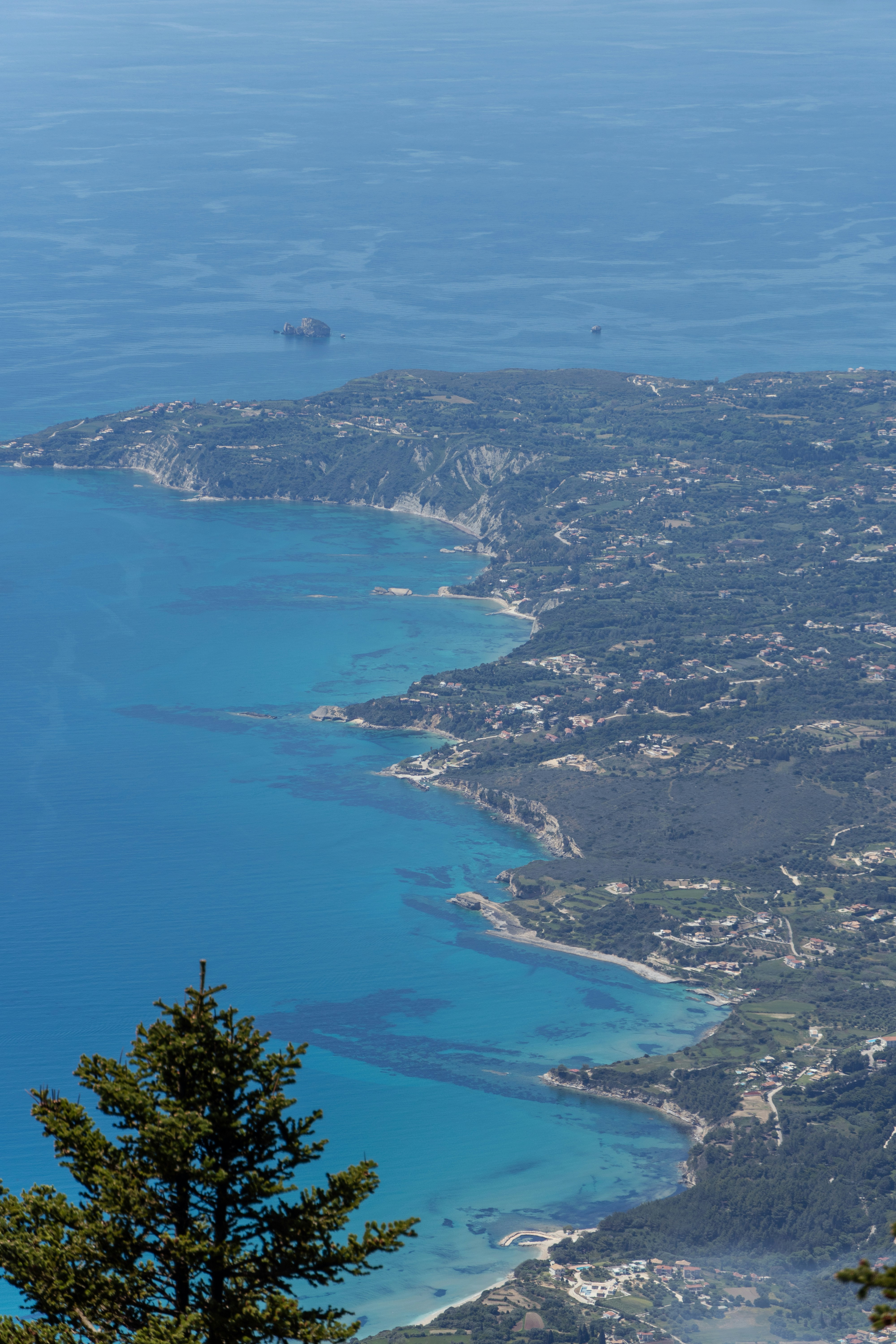 Coastal landscape with blue ocean and green hills.