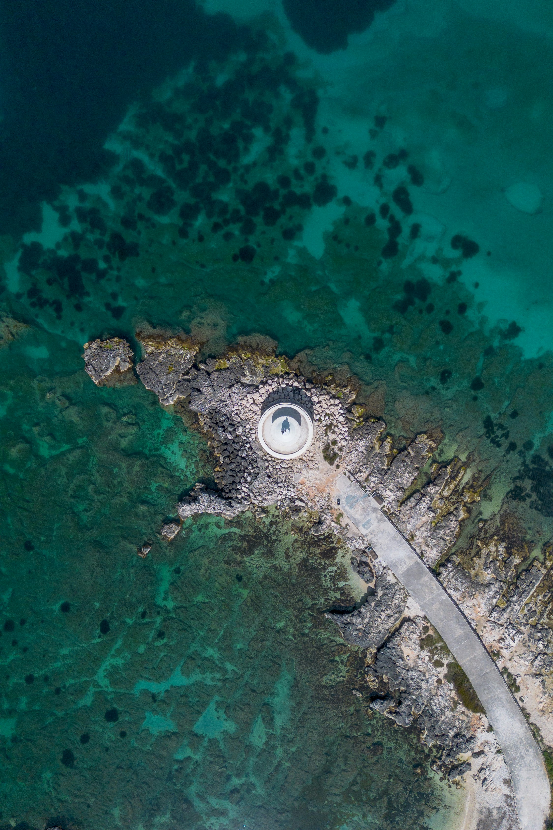Aerial view of a lighthouse on a rocky island coast.