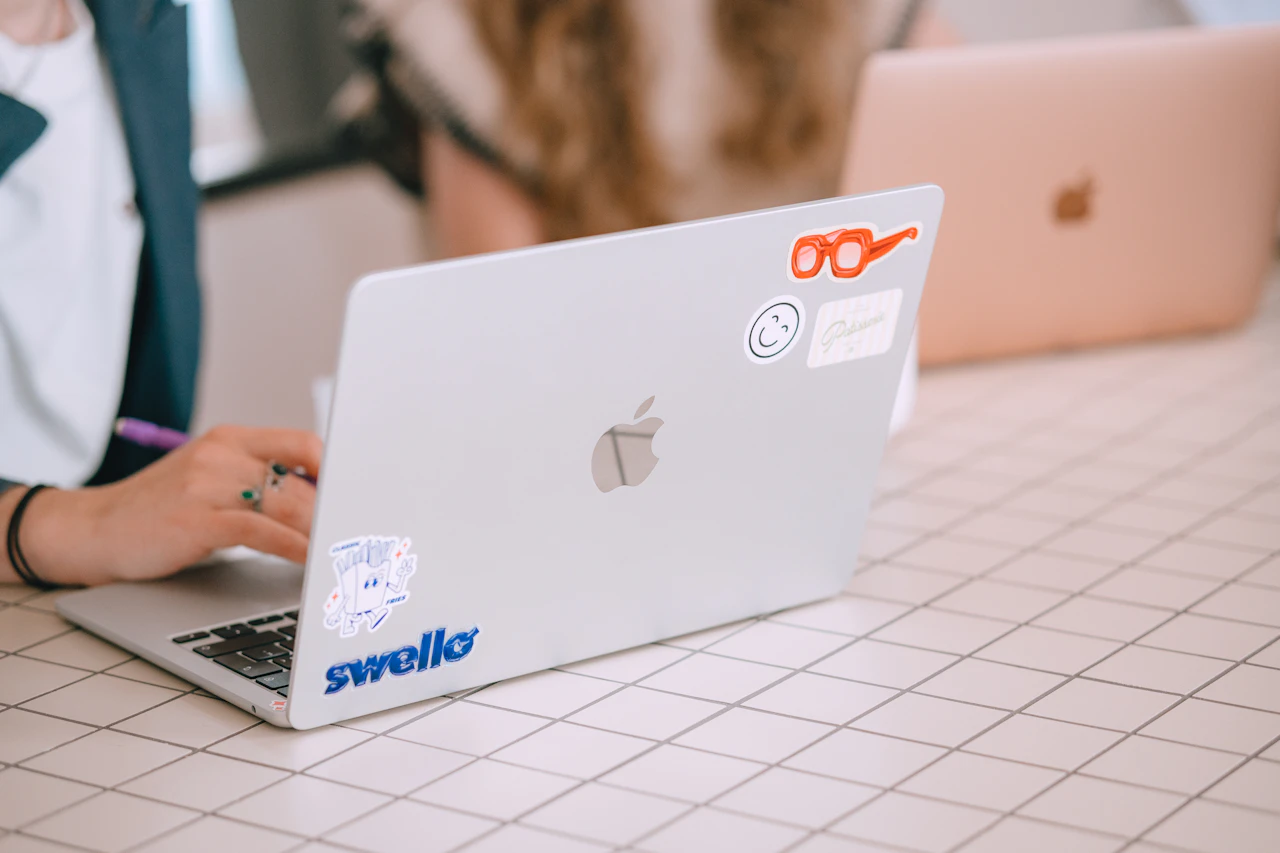 Person typing on a laptop covered in stickers