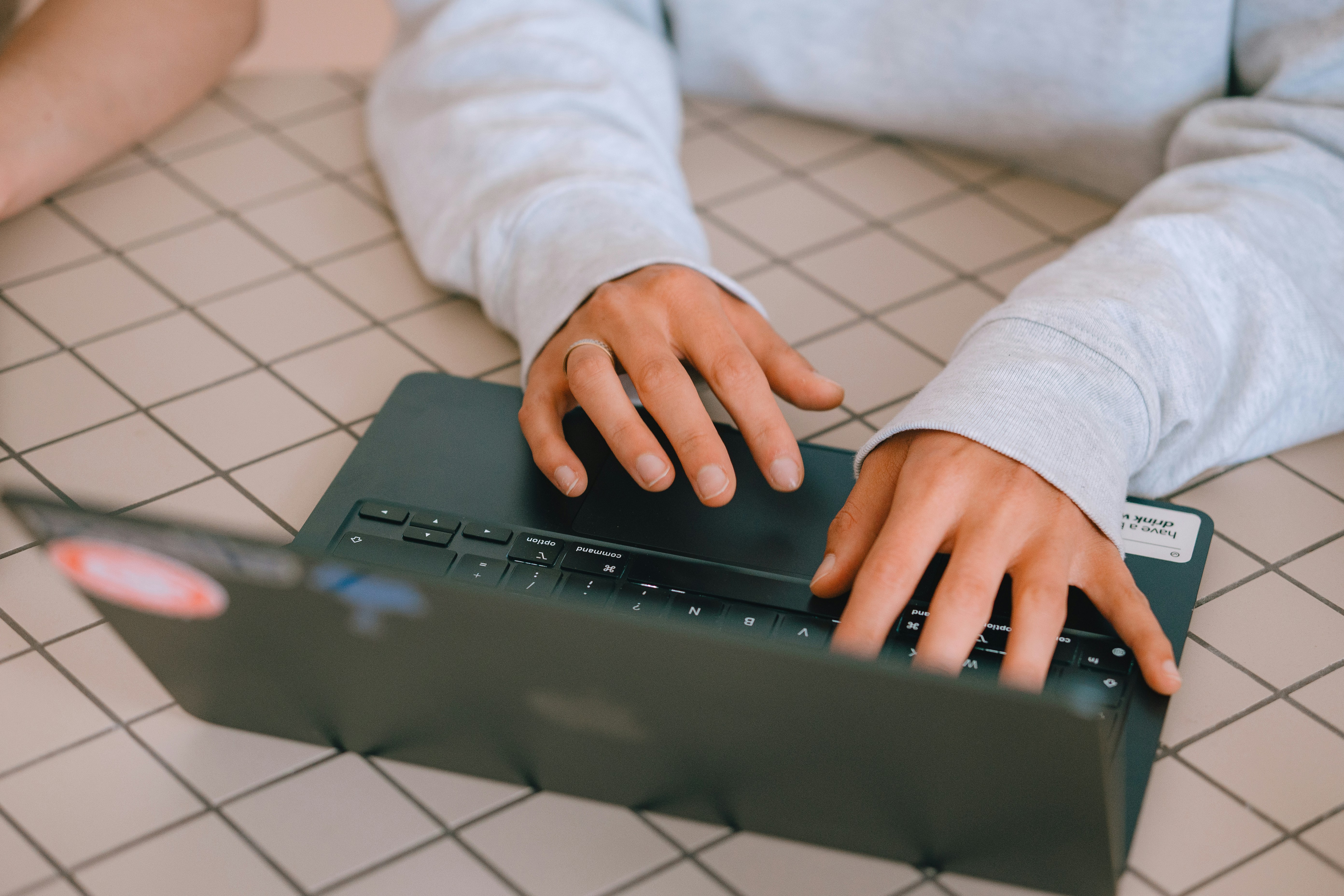 Person typing on a laptop computer on a checkered surface.