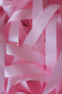 Soft pink ribbons tangled together in a pile.
