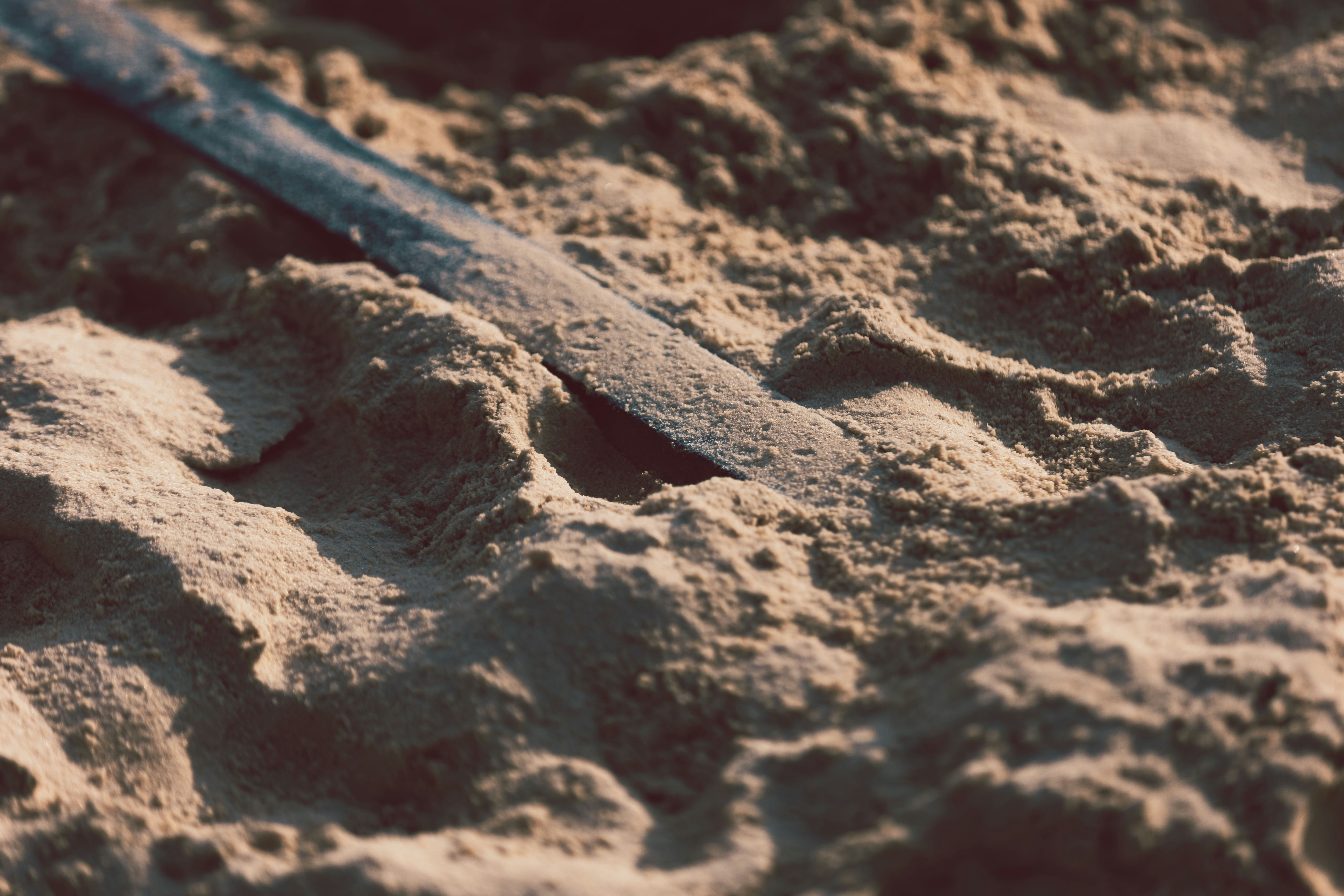 A metal rod lies partially buried in sand.