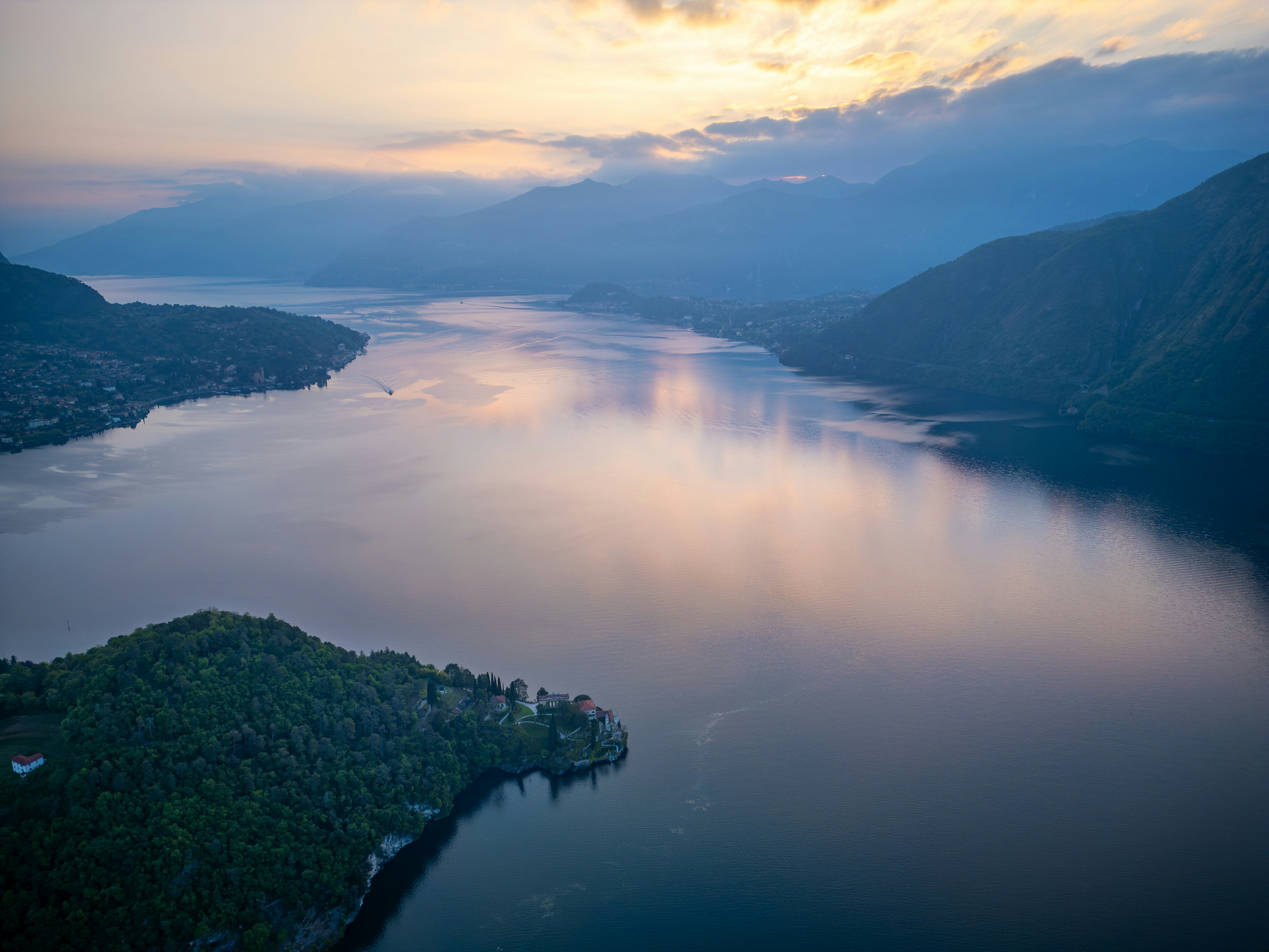 Calm lake surrounded by mountains at sunset