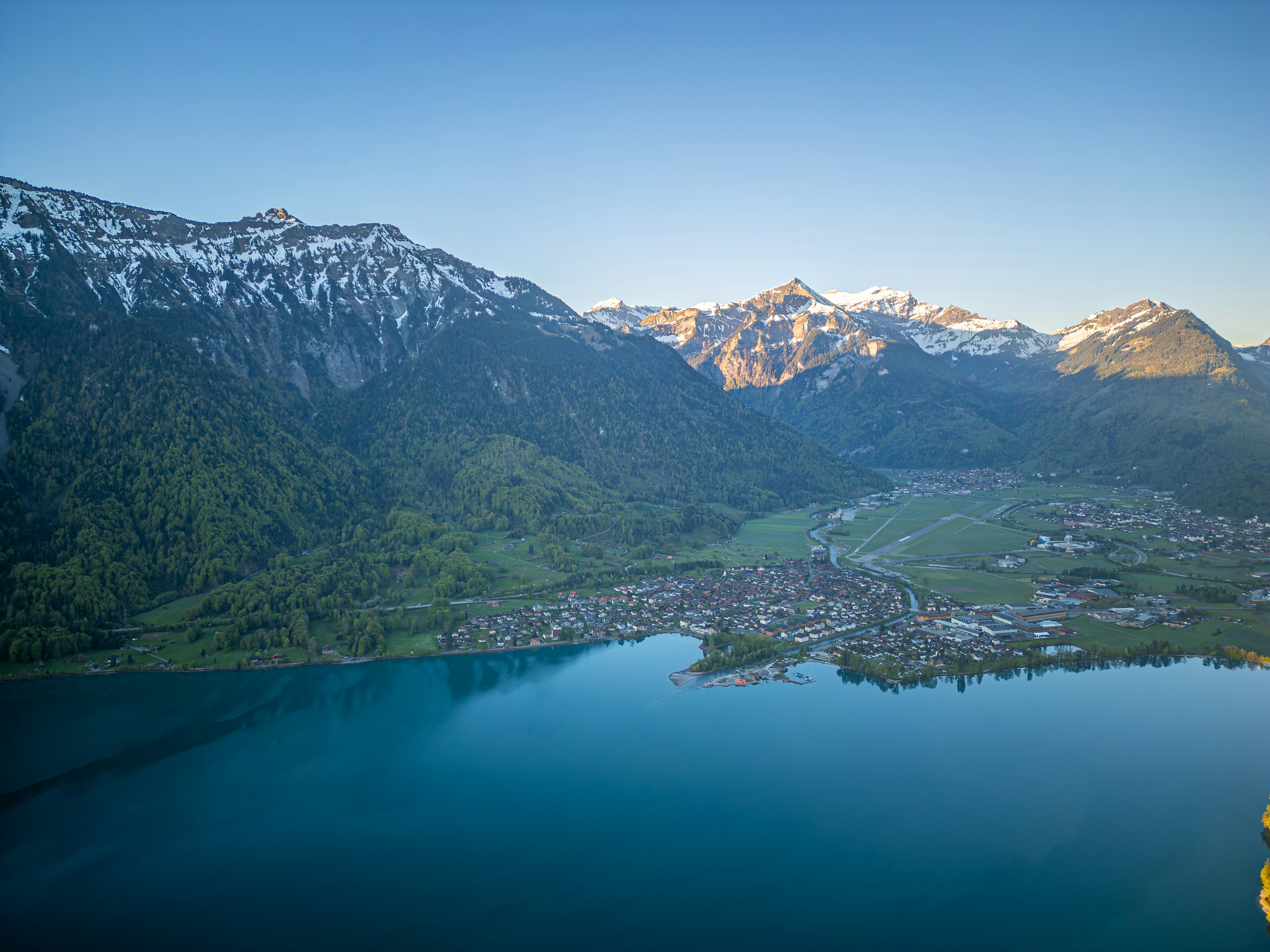 A serene lake with snow-capped mountains and a village.