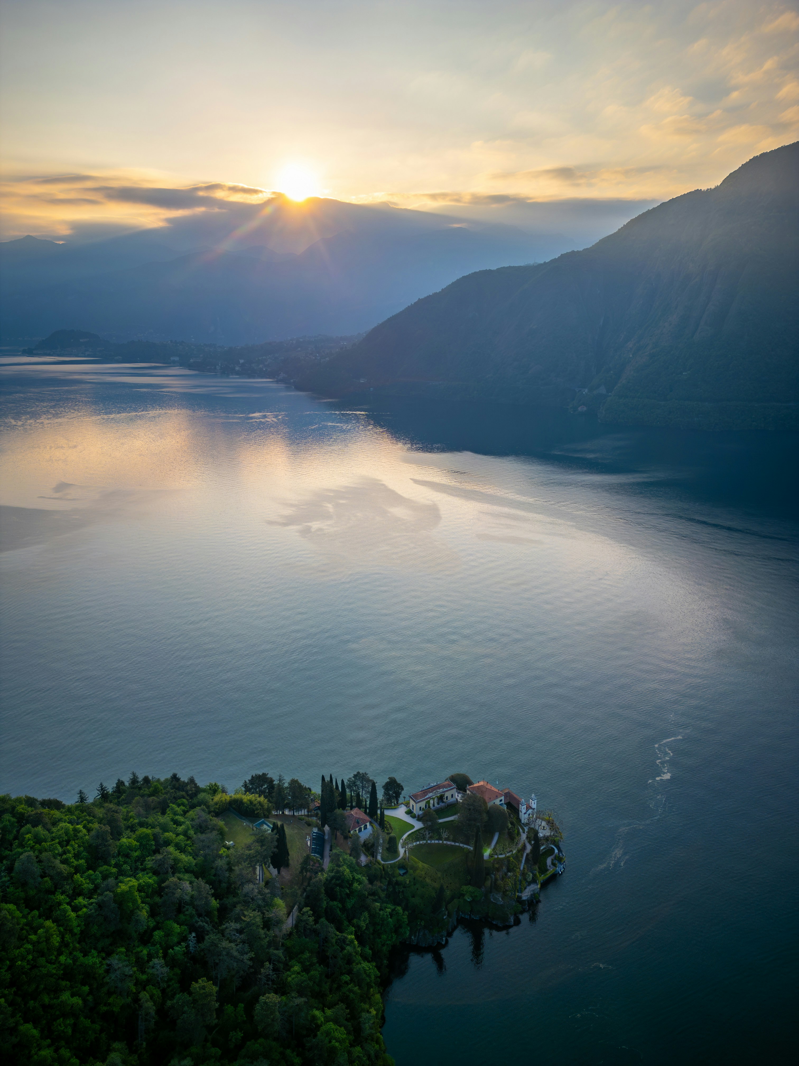 Sunrise over a tranquil lake with a small island.