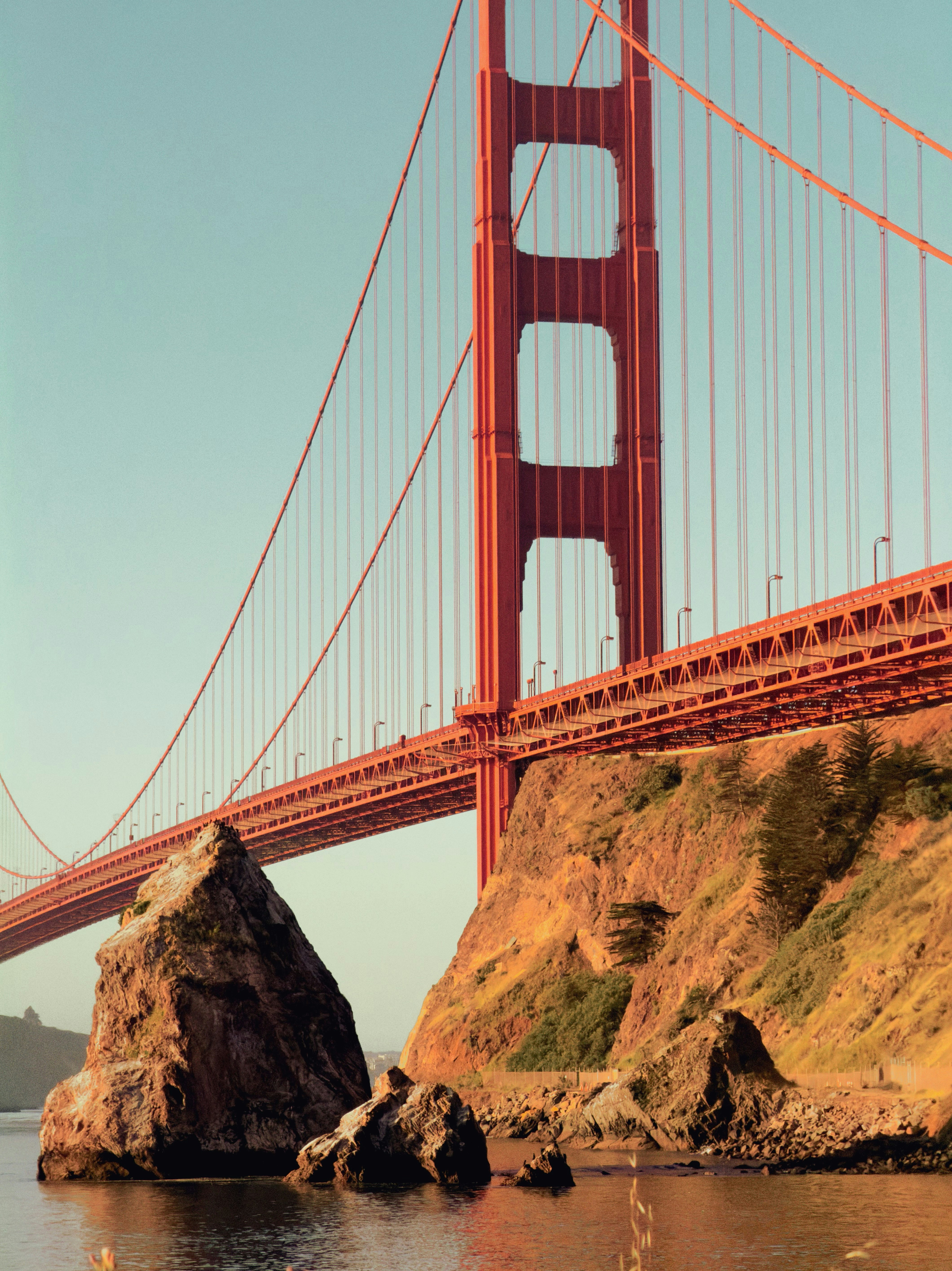 The golden gate bridge towers over rocky coastal cliffs.