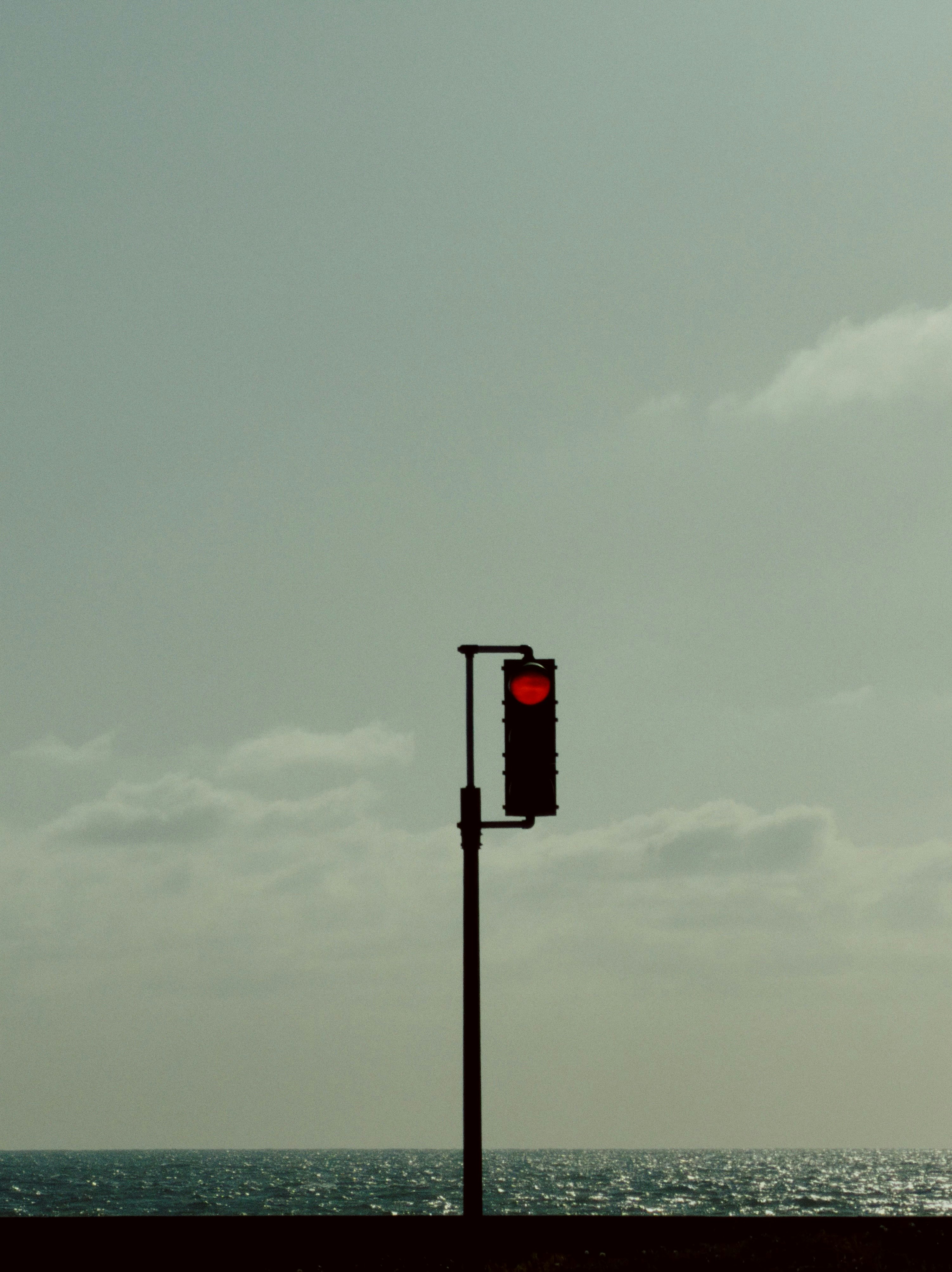 Traffic light showing red against the ocean.