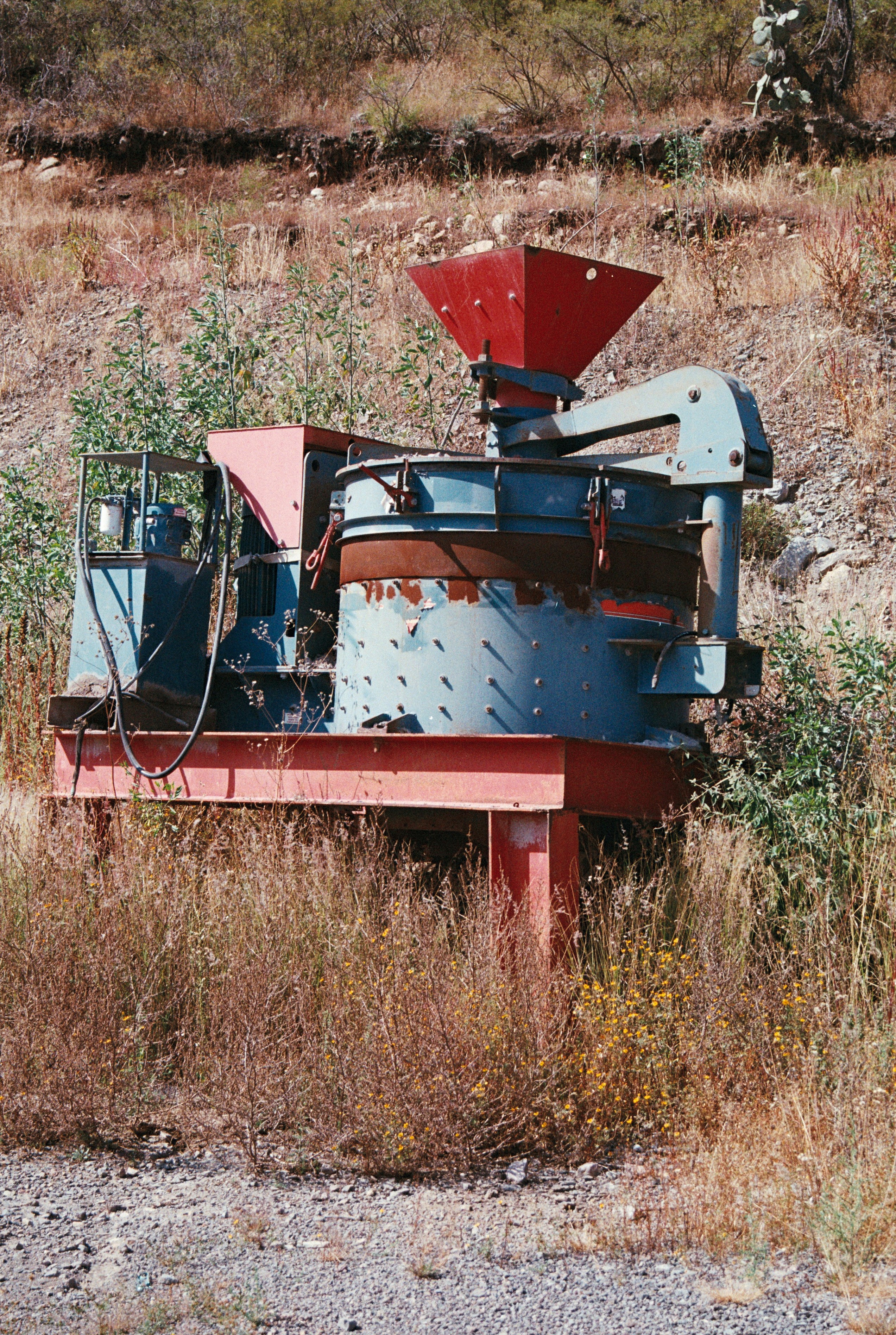 Alte Industriemaschinen stehen auf einem überwucherten Feld.