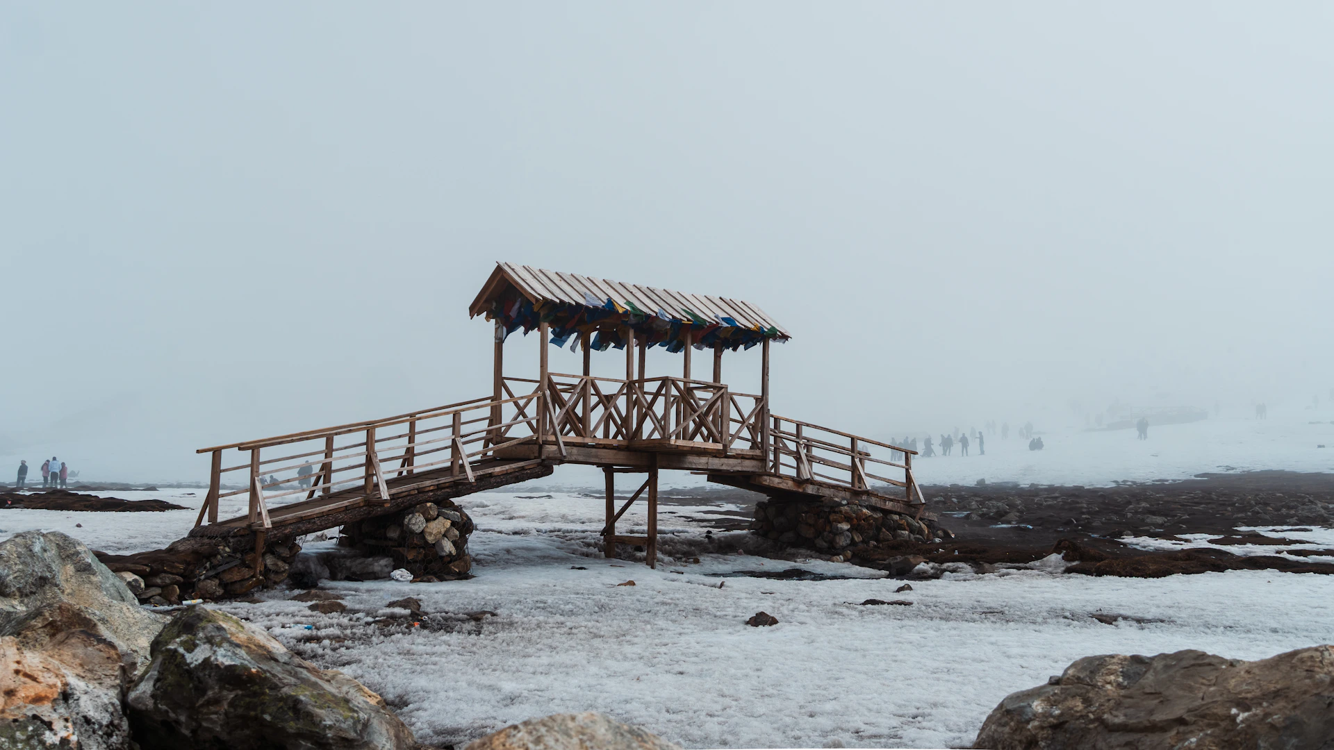 Wooden bridge with thatched roof over snowy ground