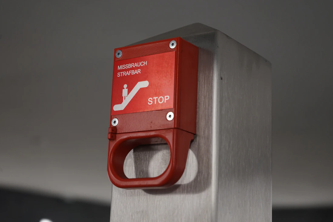 A red emergency stop button on a metal pole