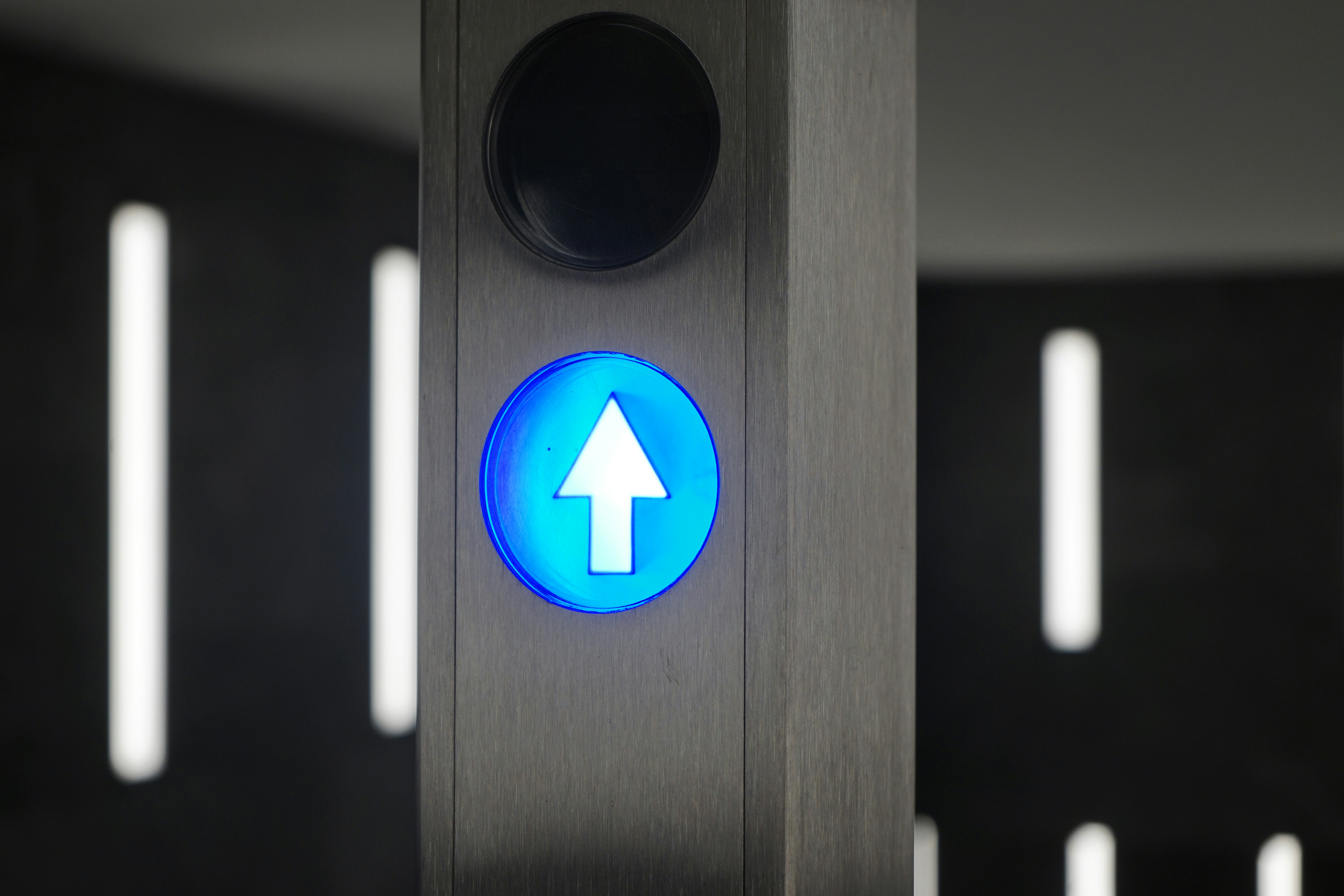 A blue illuminated arrow points upward on a pillar.