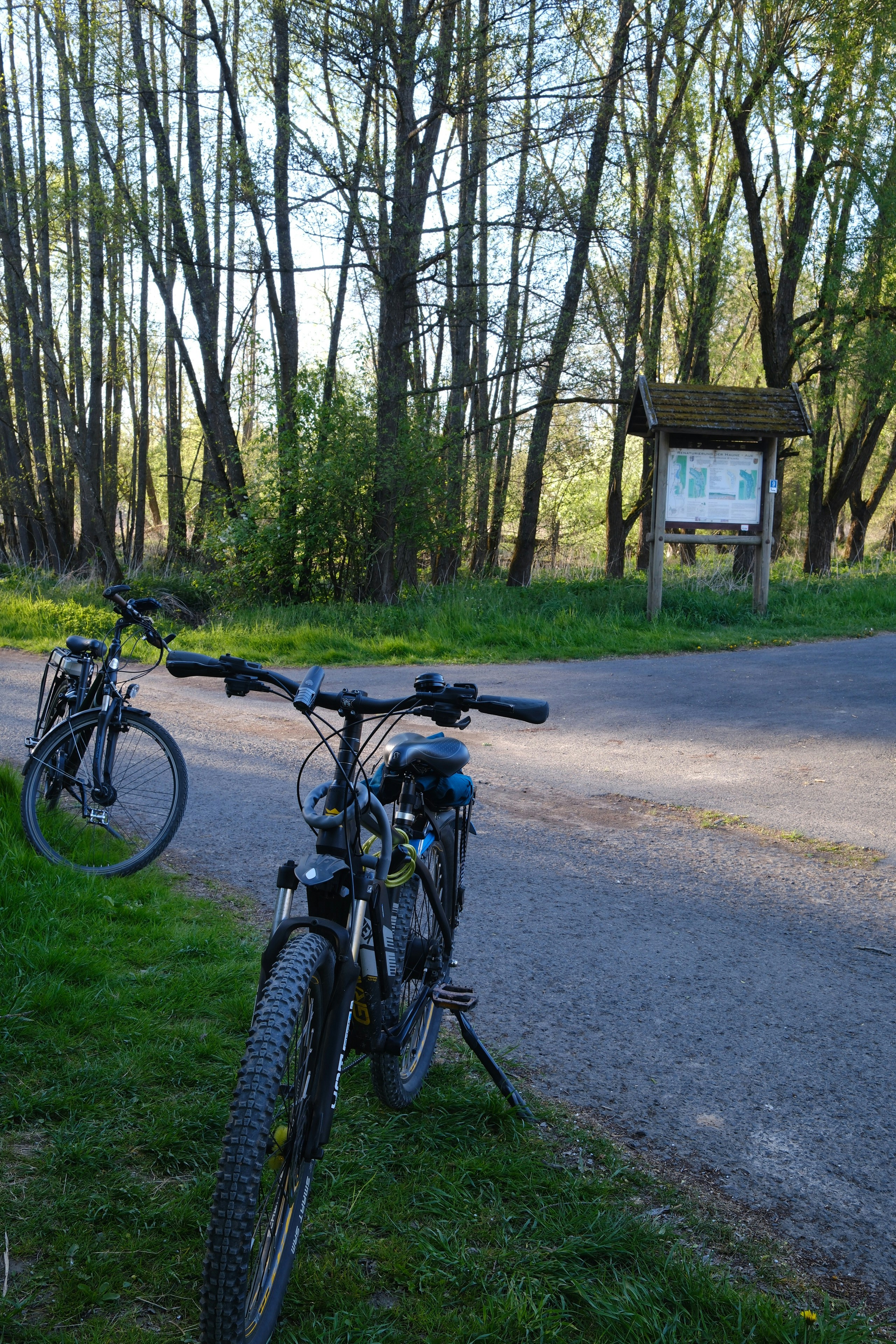 Two bicycles parked near a wooden information sign.