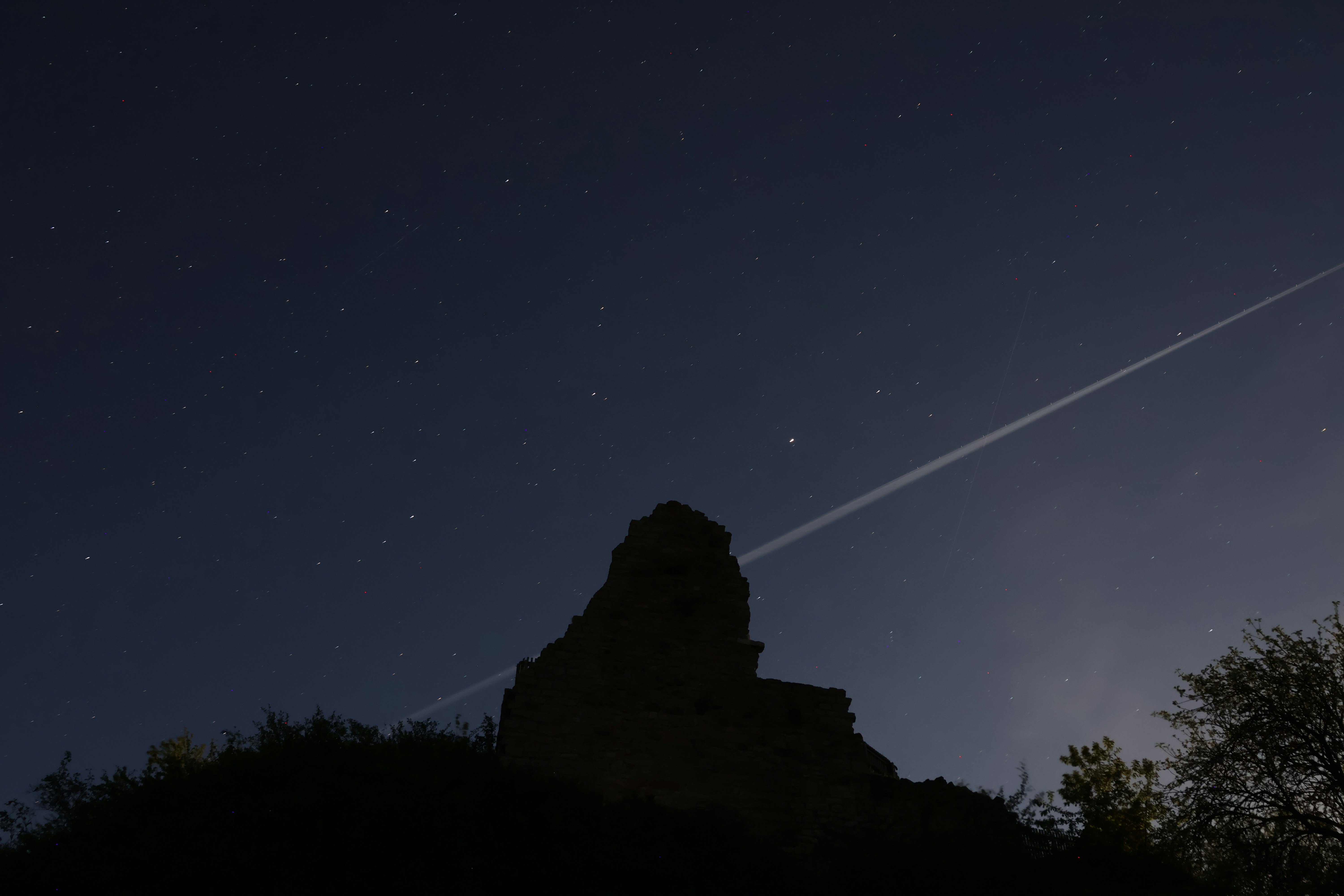 Silhouette of a rocky peak against a starry night sky. (Photo by Viktor Friesen on Unsplash)
