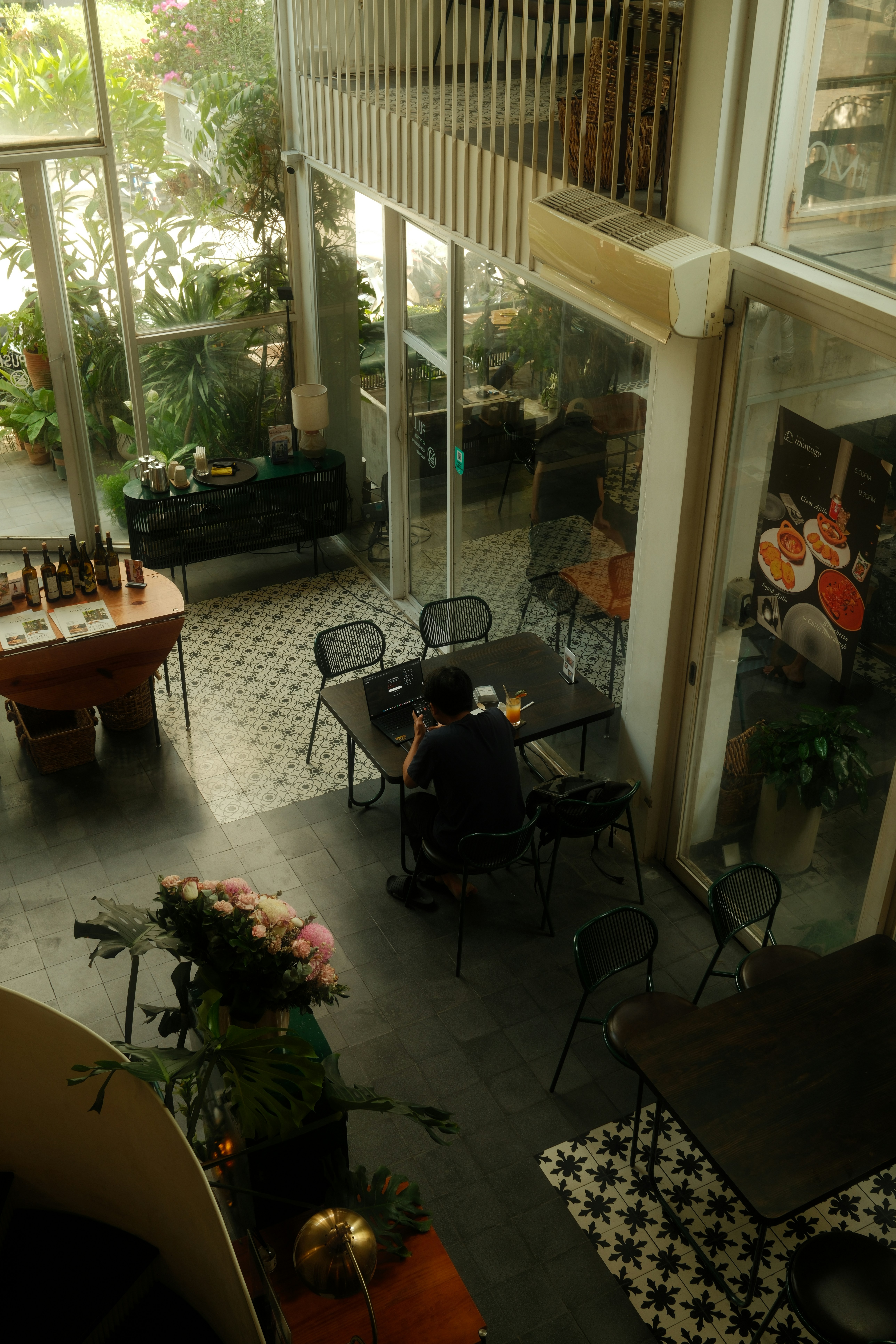 Una persona è seduta a un tavolo in un caffè luminoso.