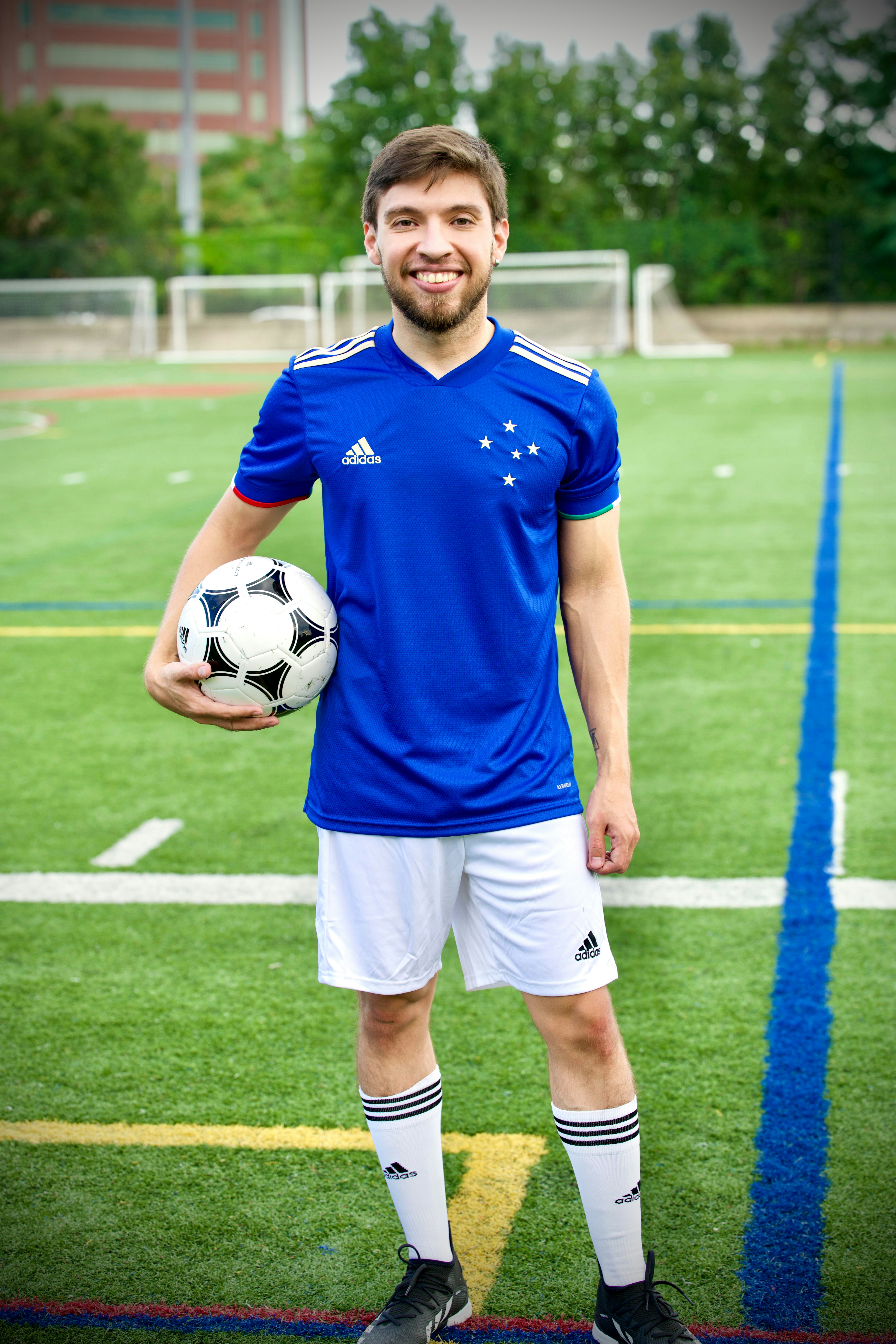 Un hombre sonriente con uniforme de fútbol sosteniendo un balón