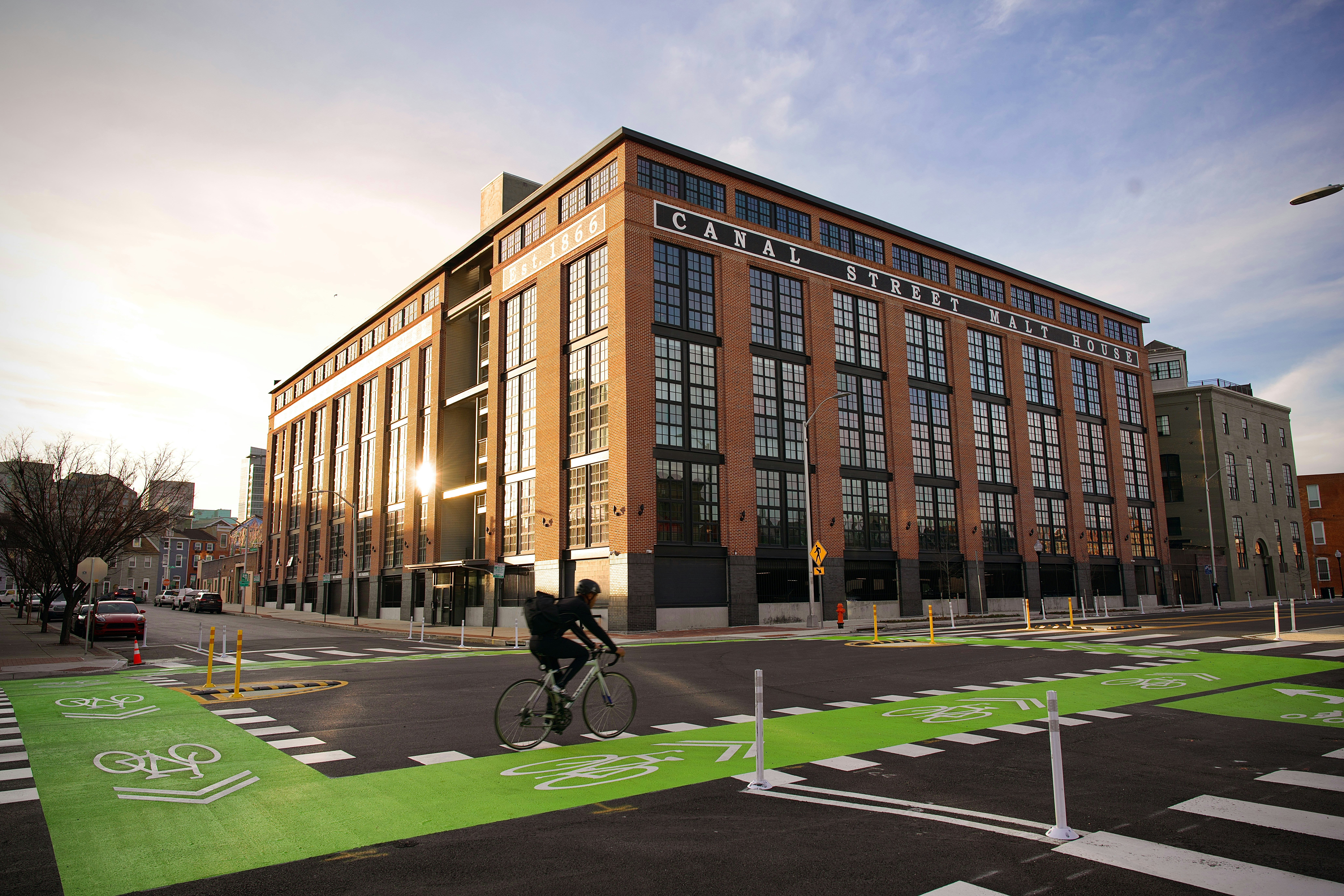 Ciclista en un carril bici verde brillante cerca de un edificio.