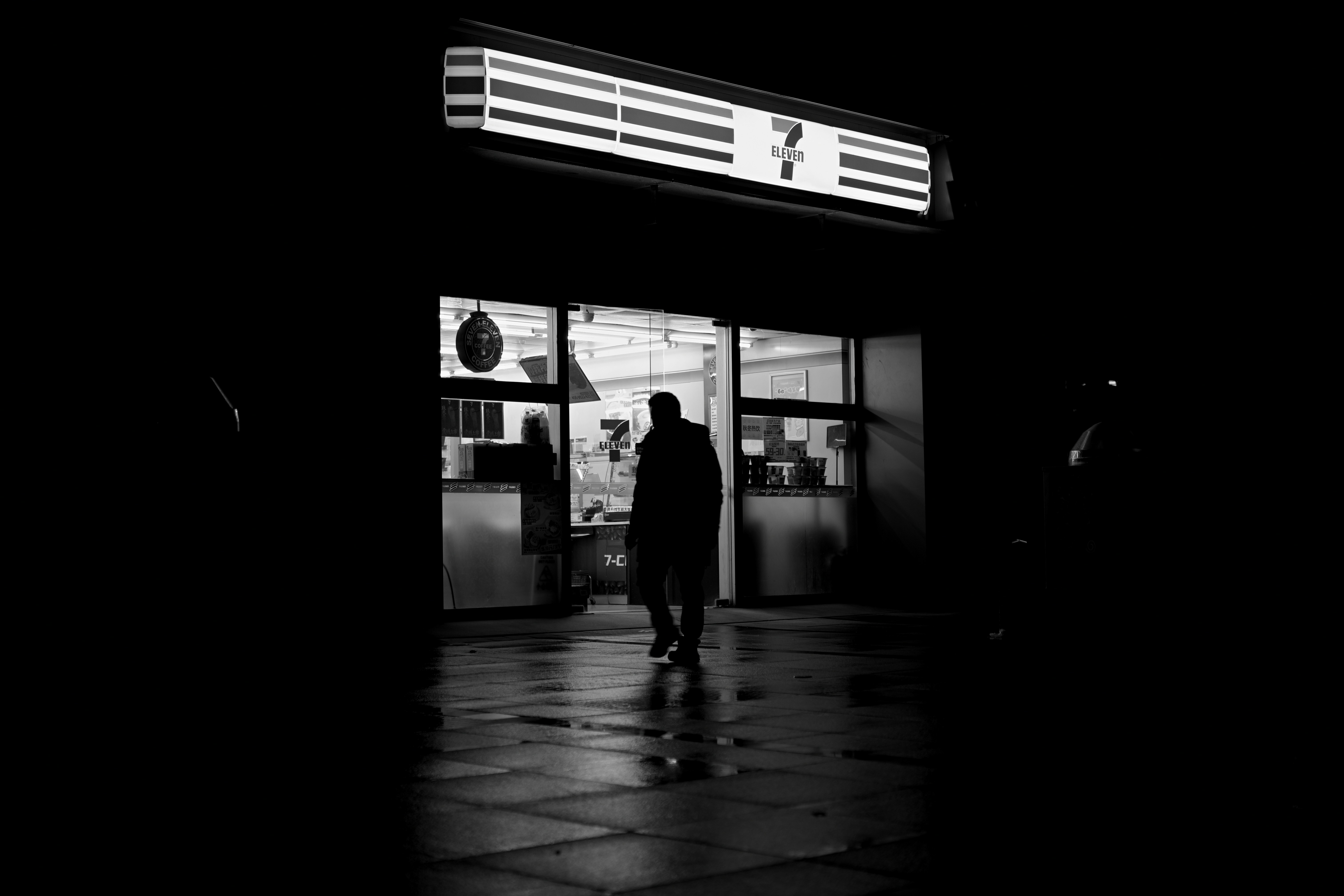 Man walks into a brightly lit store at night
