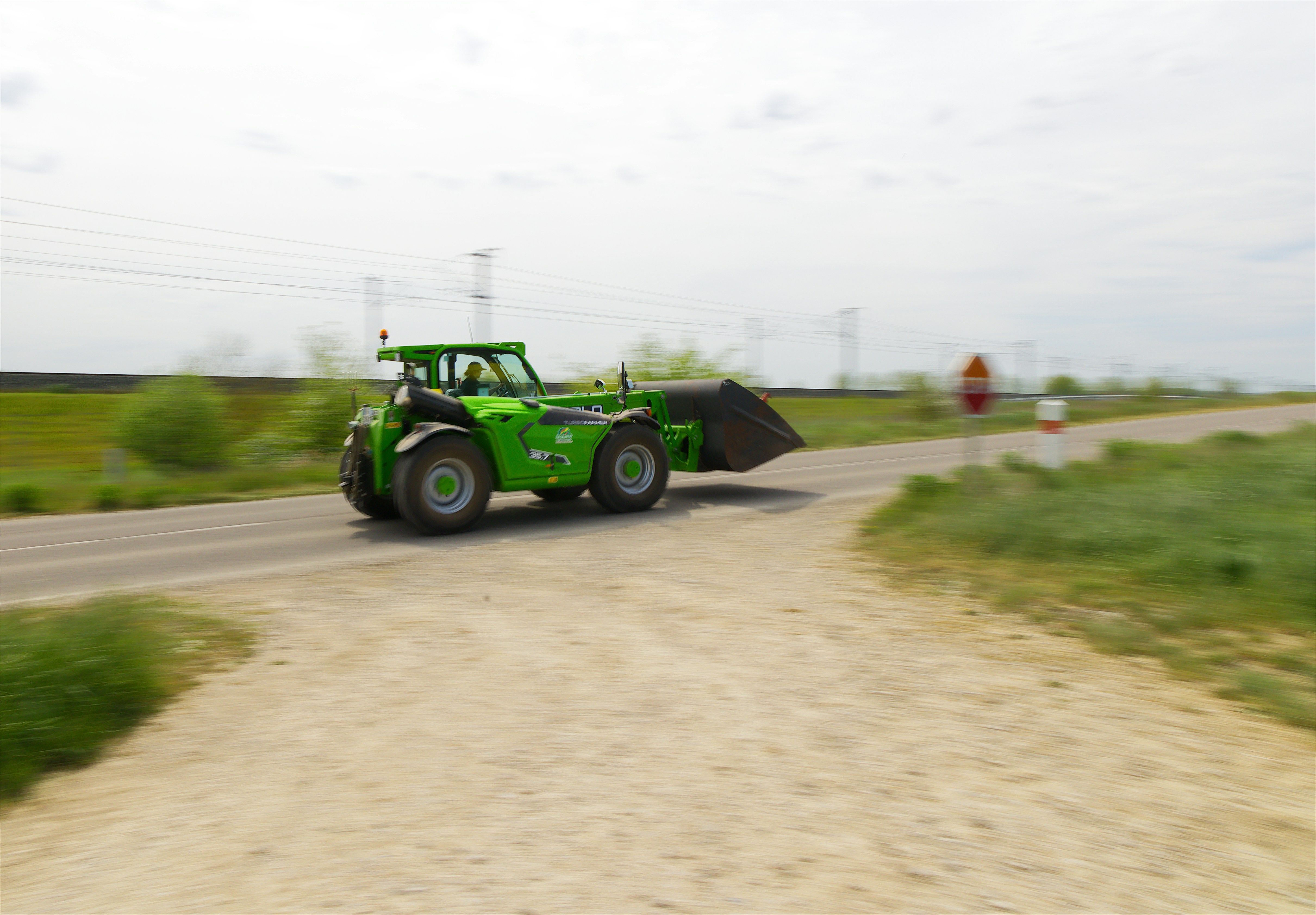 A green tractor drives down a rural road.