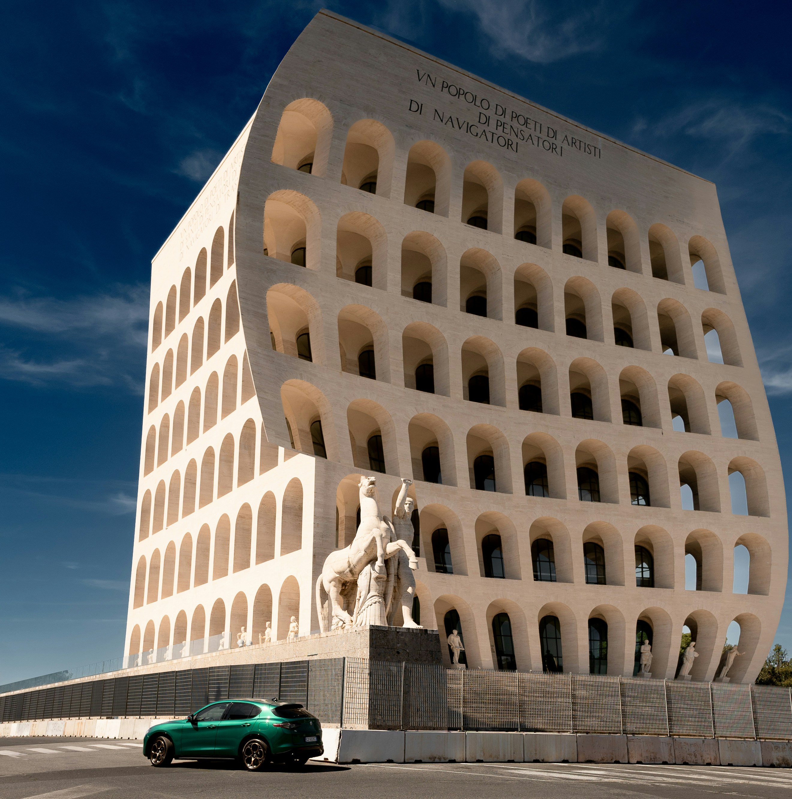Edificio moderno con ventanas arqueadas y esculturas de caballos.
