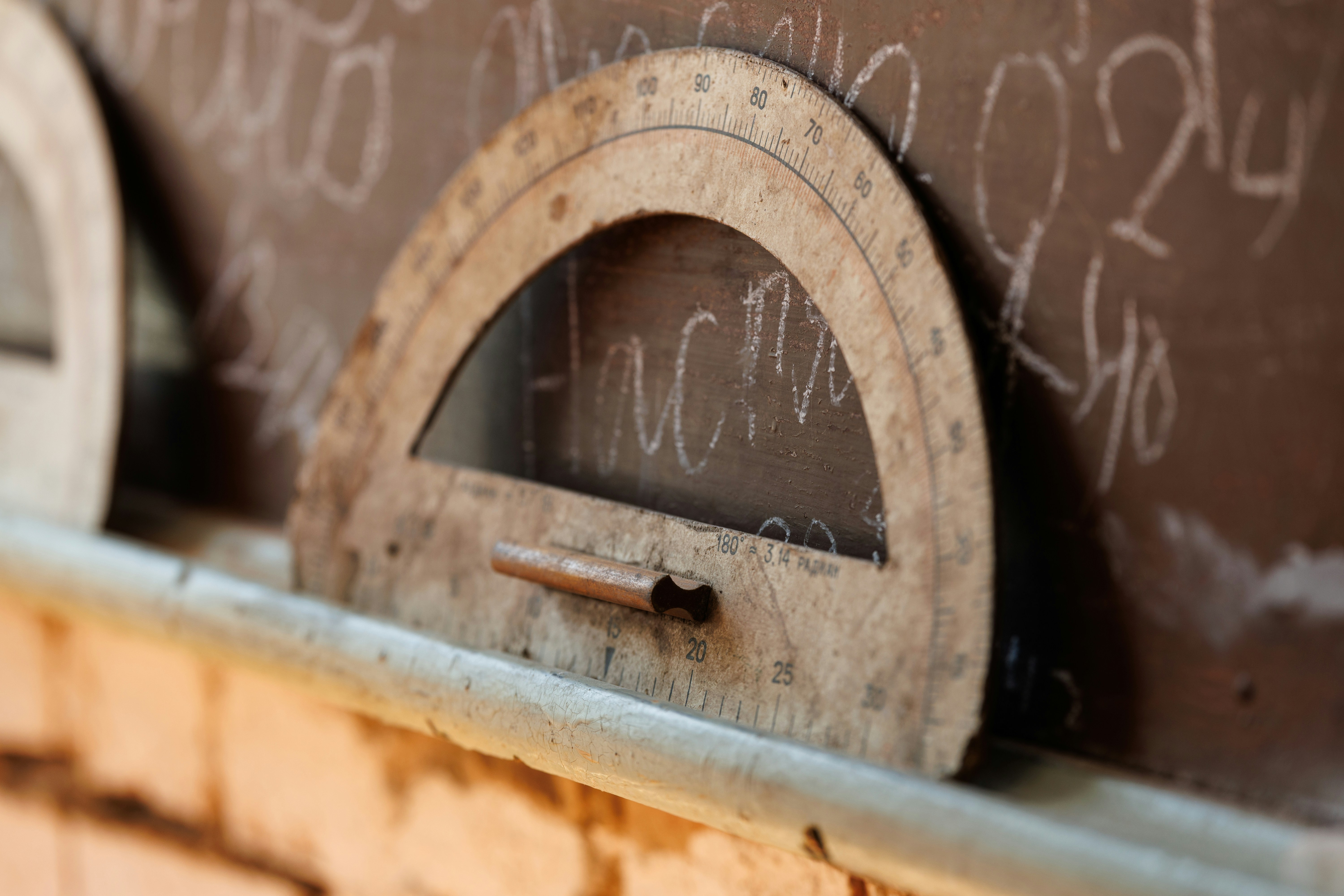 A wooden protractor rests on a chalkboard
