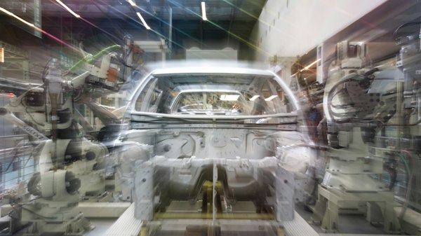 Línea de ensamble automotriz con brazos robóticos trabajando sobre una carrocería, terreno de la agencia de marketing digital para industria automotriz