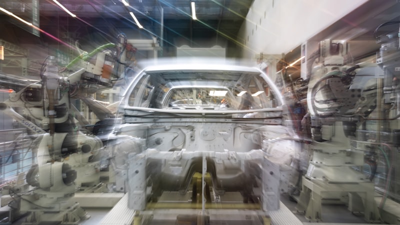 Car assembly line with robotic arms and car body.