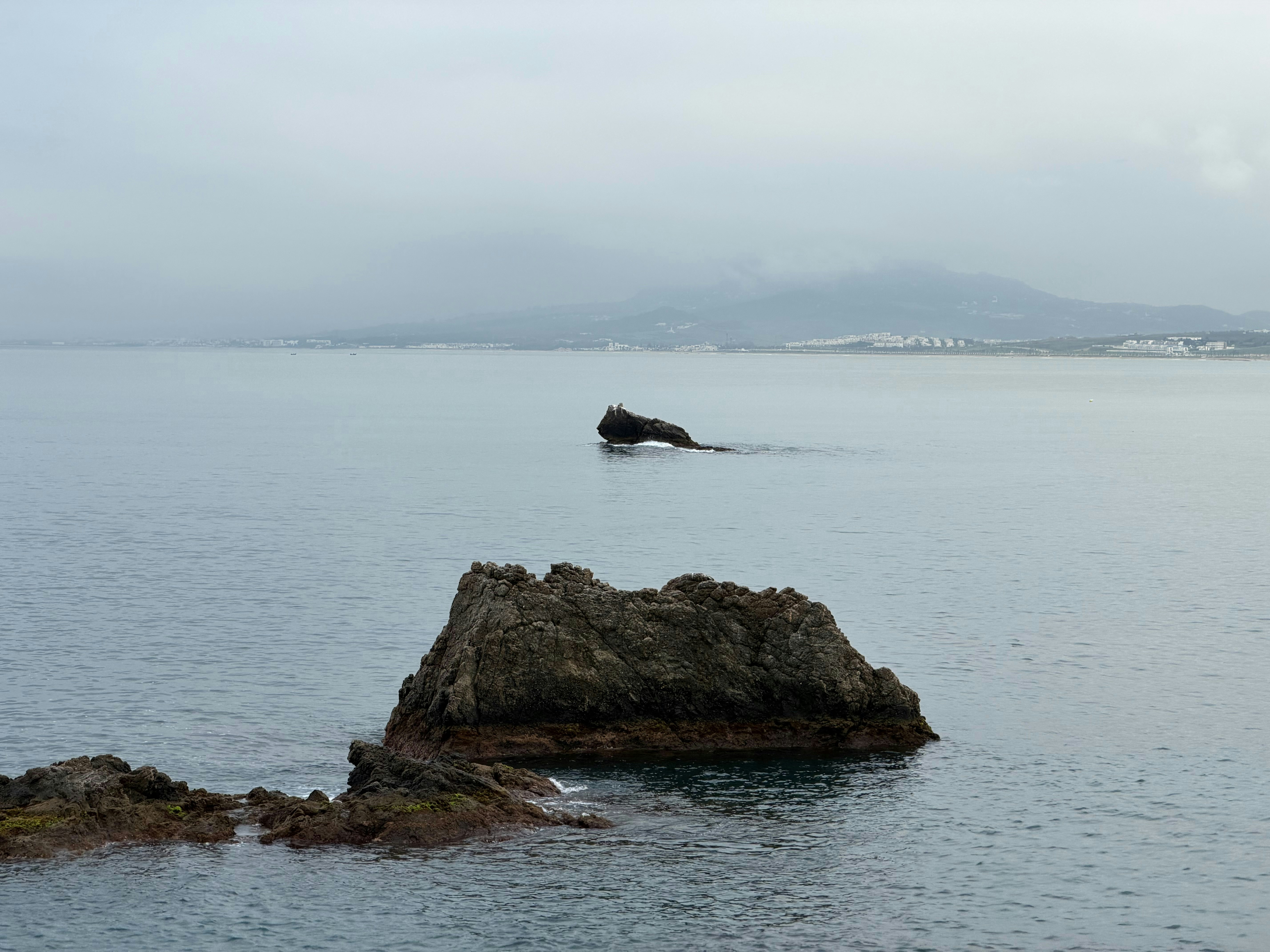 Rocks in the calm ocean water with distant land