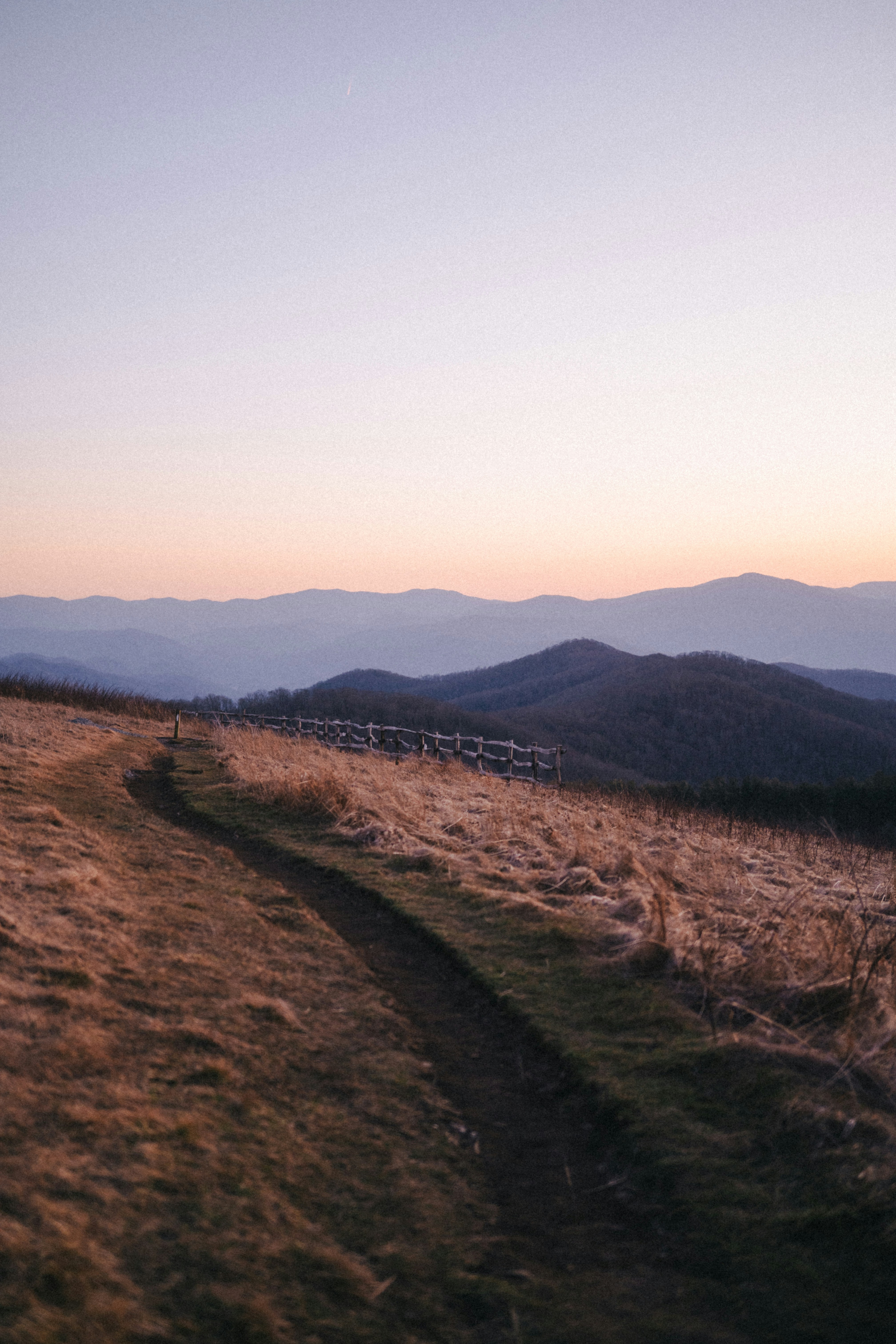 Um caminho sinuoso de terra por uma encosta gramada ao pôr do sol.