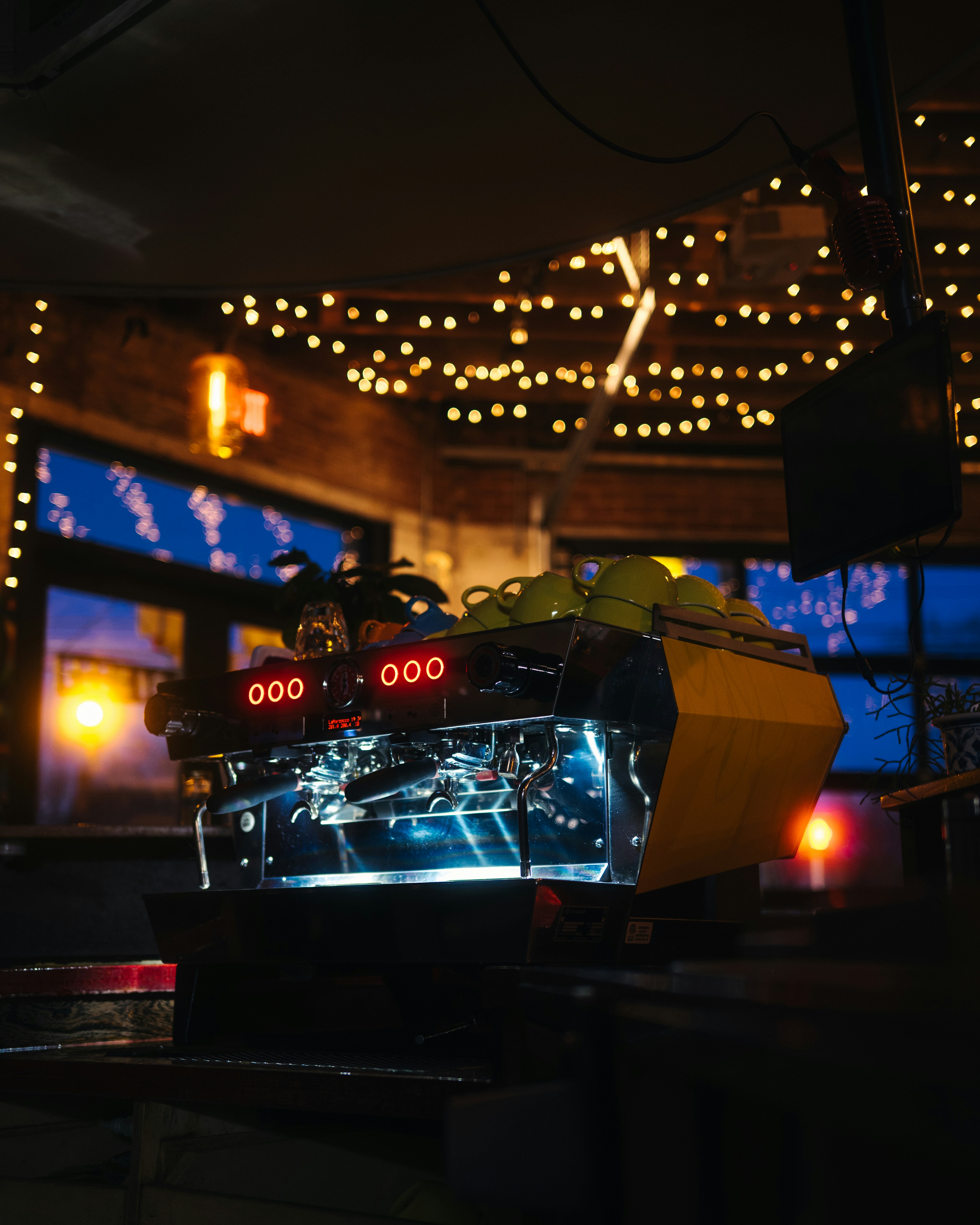Máquina de espresso com luzes brilhantes em um café pouco iluminado.