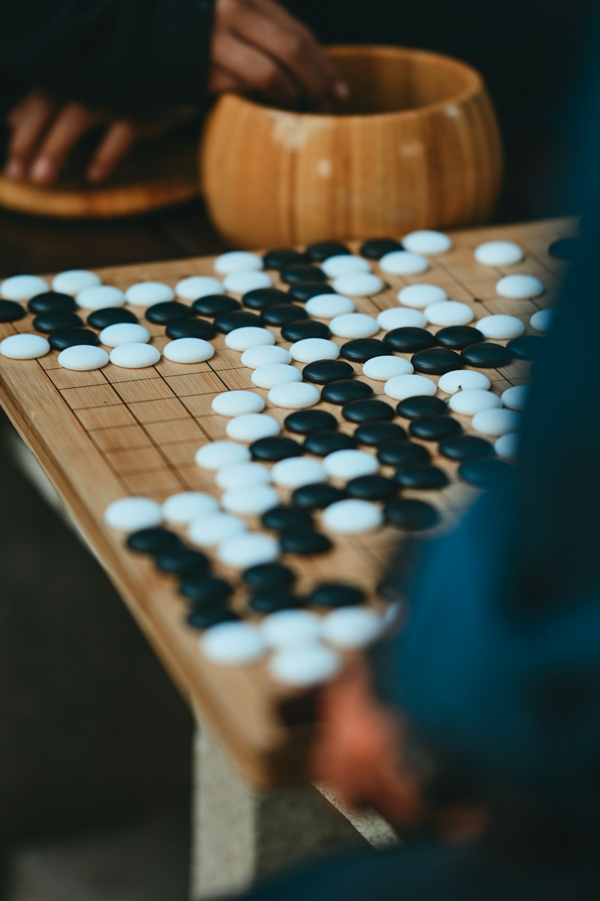 A game of Go in progress on a wooden board with black and white stones