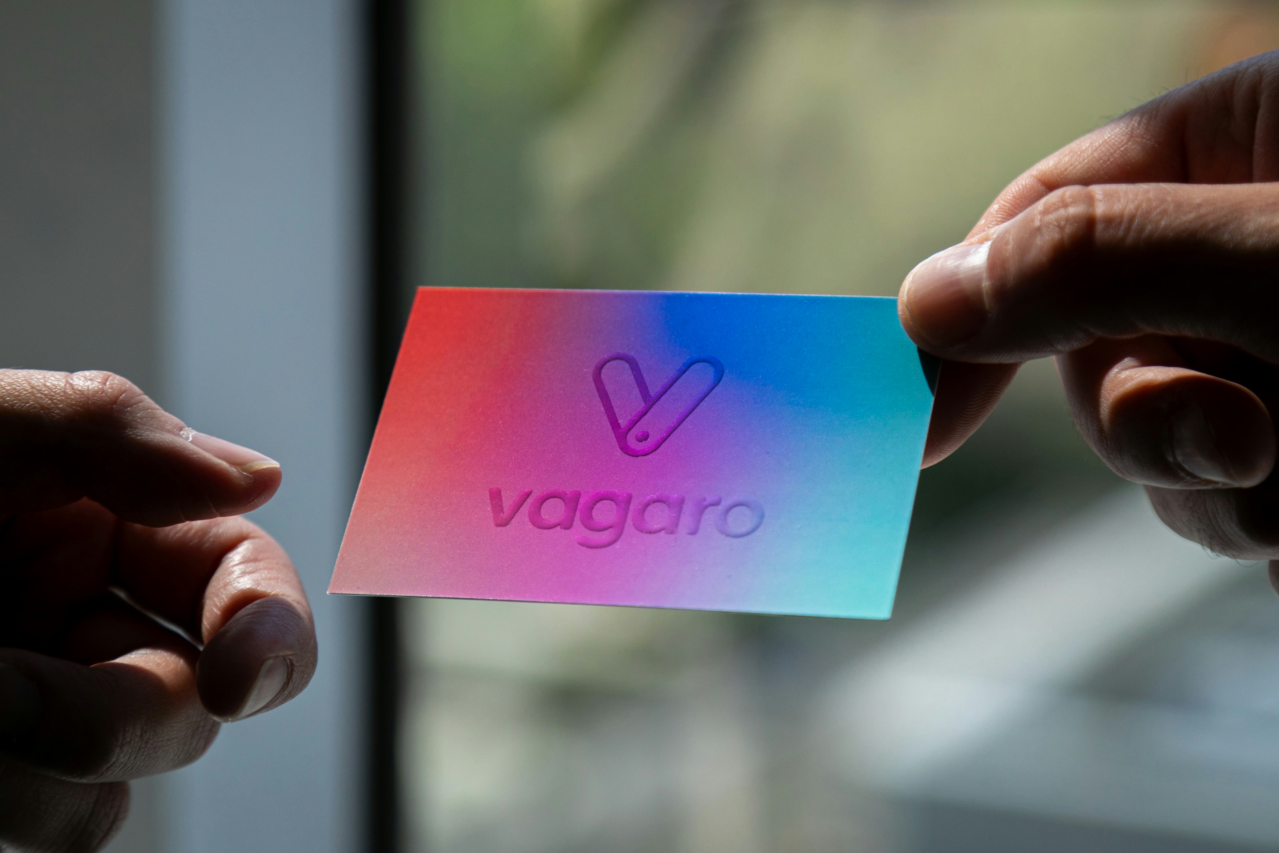 両手で「vagaro」ロゴ入りのカラフルなカードを持っています。