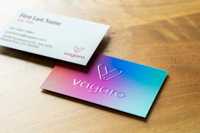 Two business cards on a wooden surface.