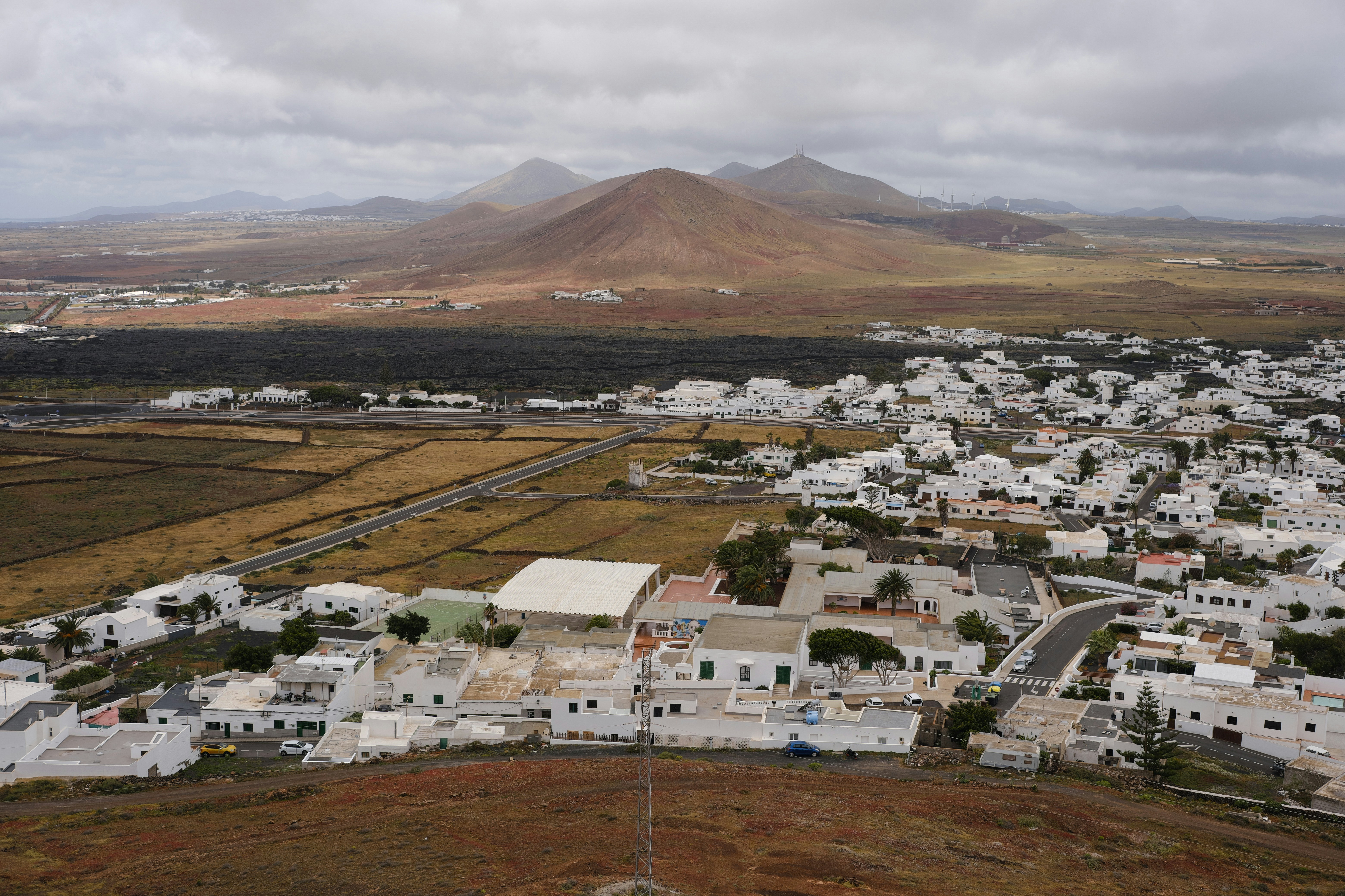 Vista aérea de uma vila branca com montanhas ao fundo.