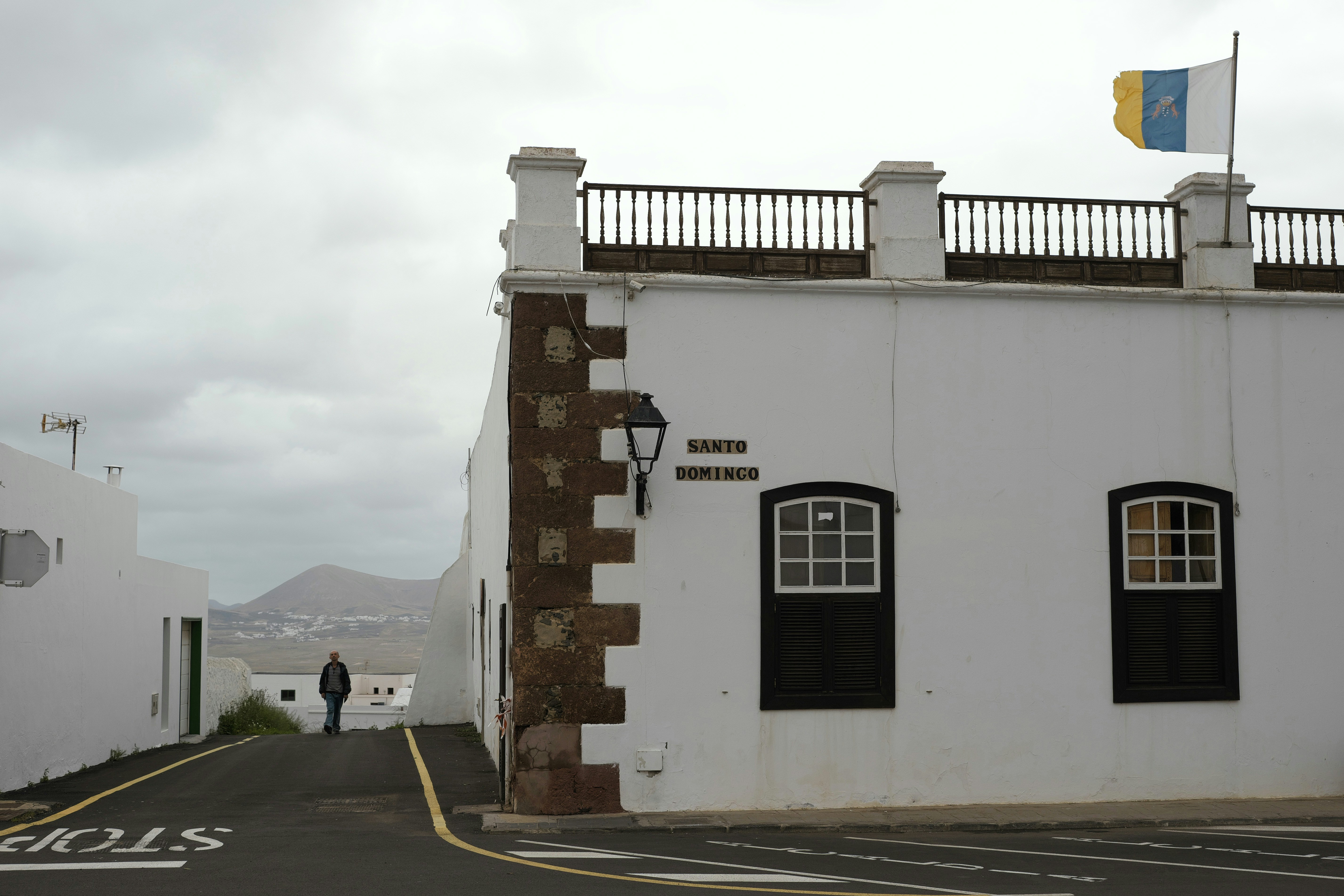 Prédio branco com bandeira e céu nublado.
