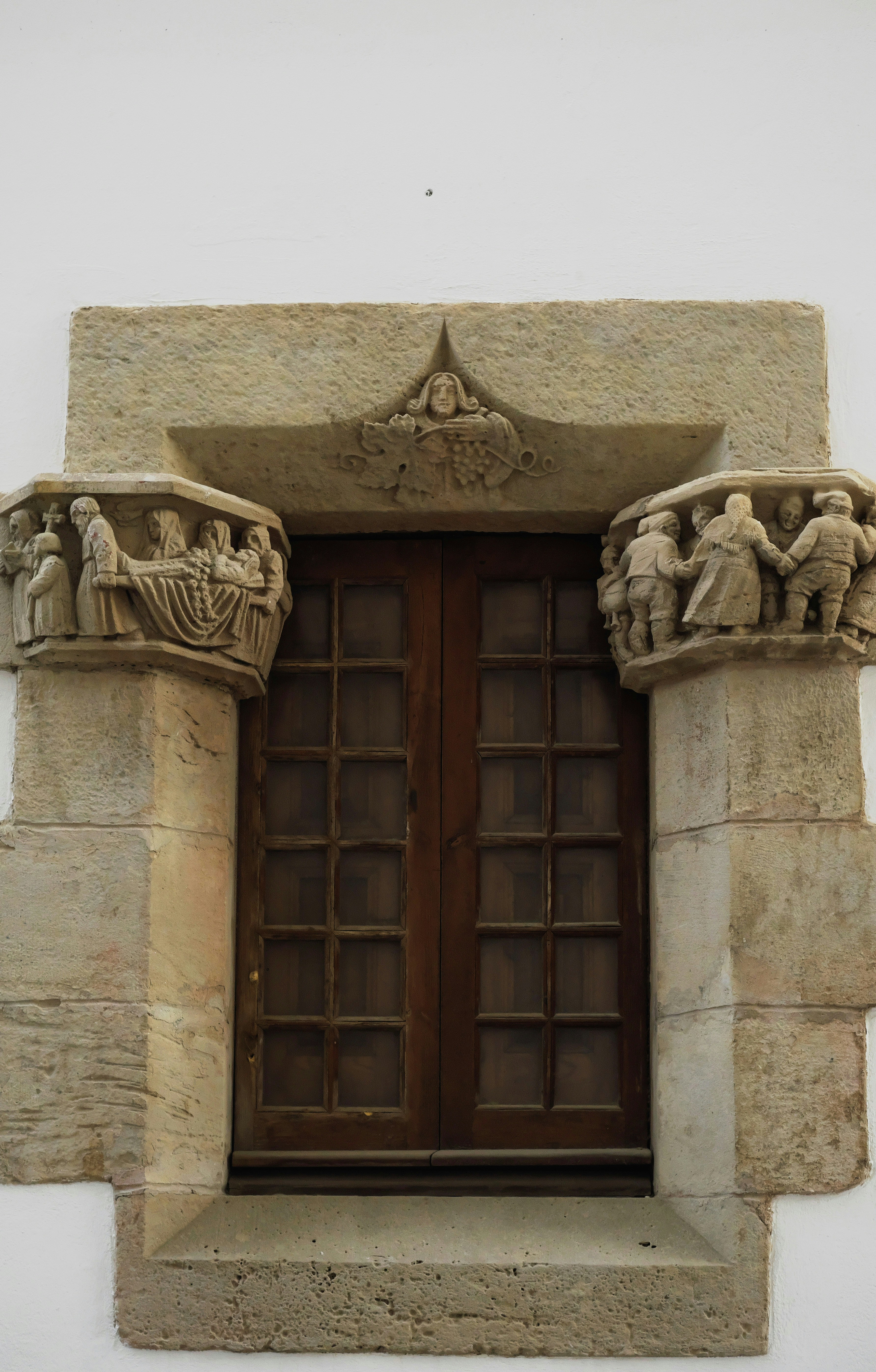 Moldura de janela de pedra com figuras esculpidas e portas de madeira