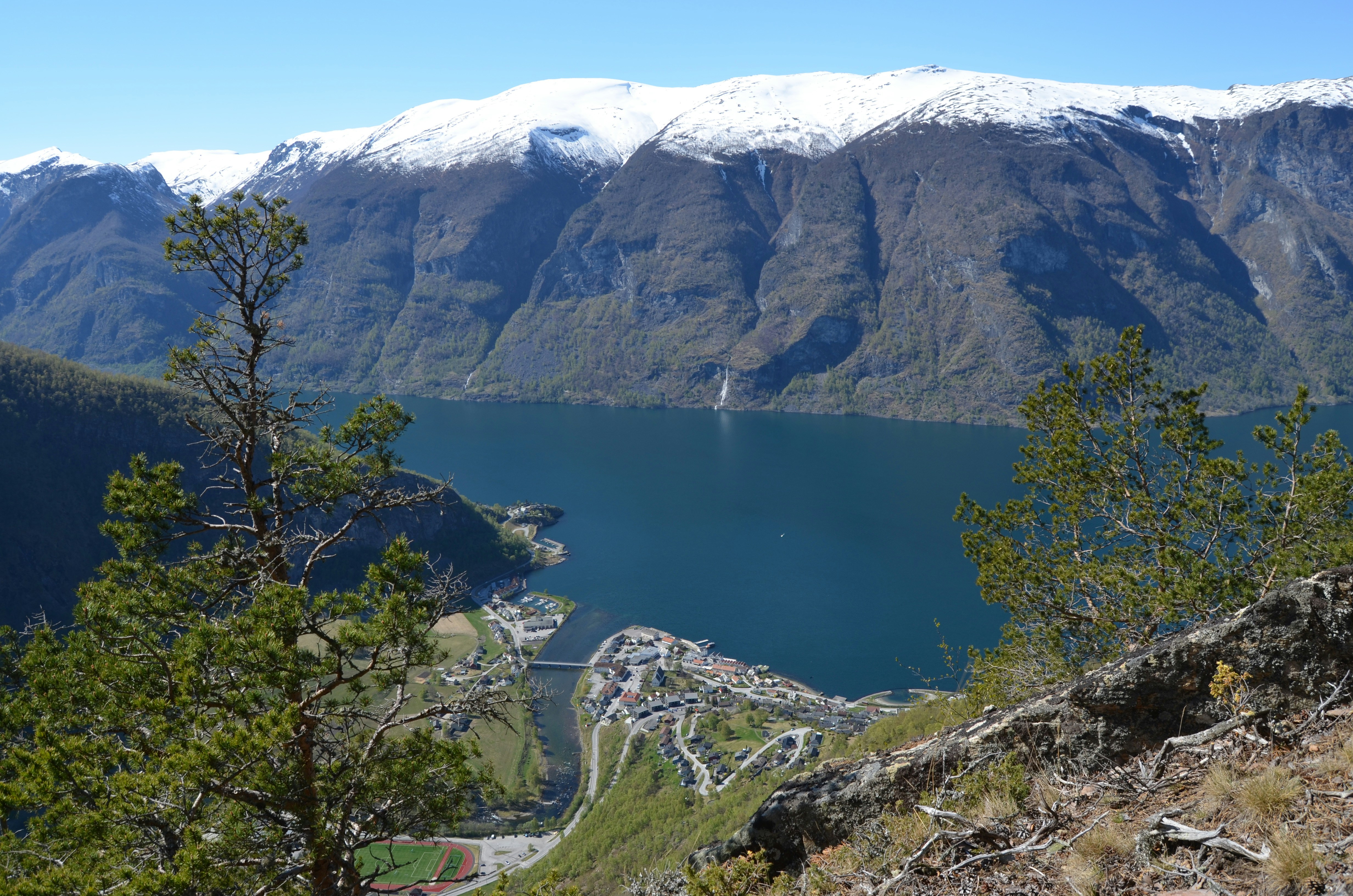 Snow-capped mountains overlook a deep blue fjord and village.