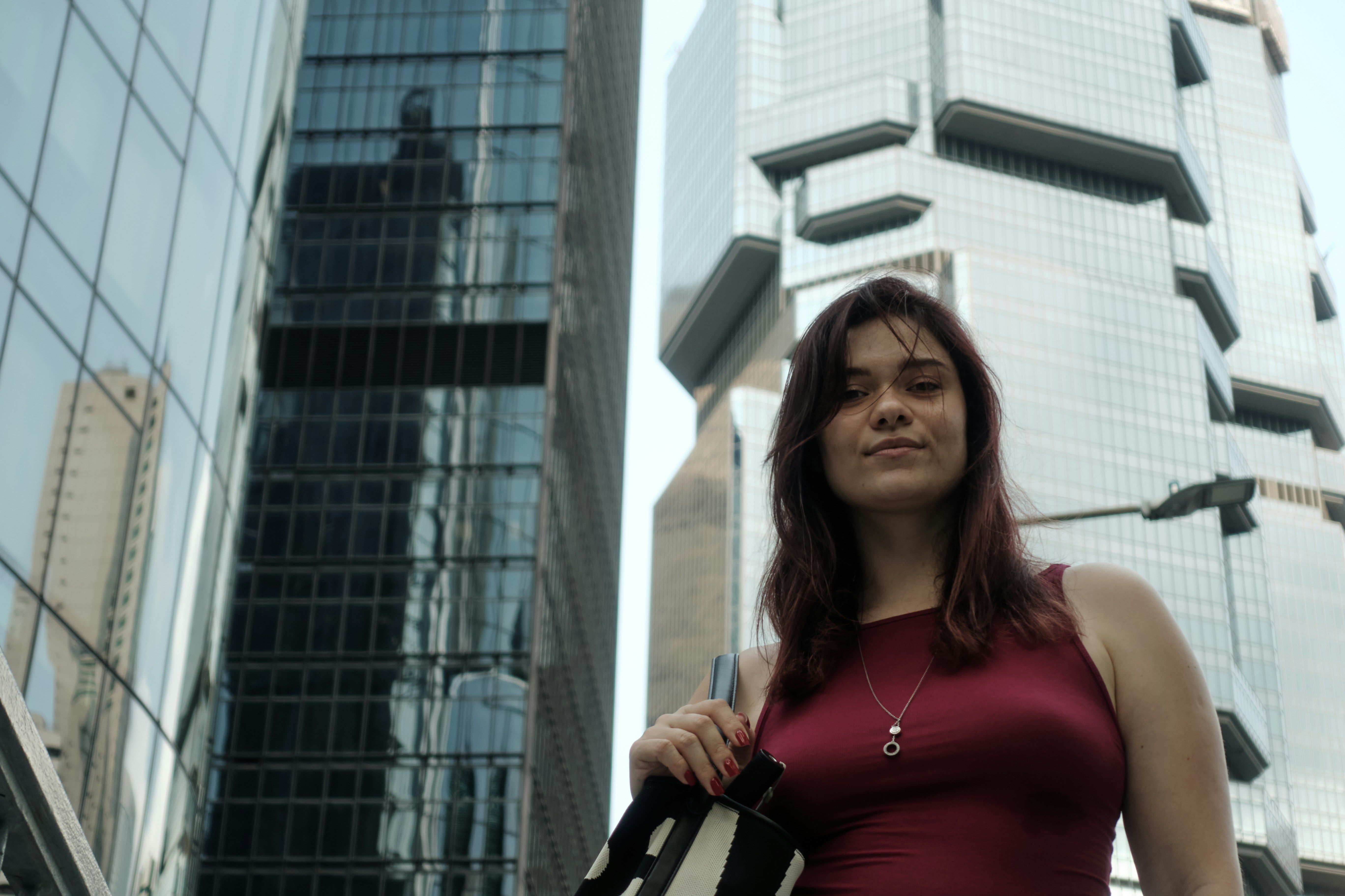 Jovem mulher está entre prédios modernos da cidade
