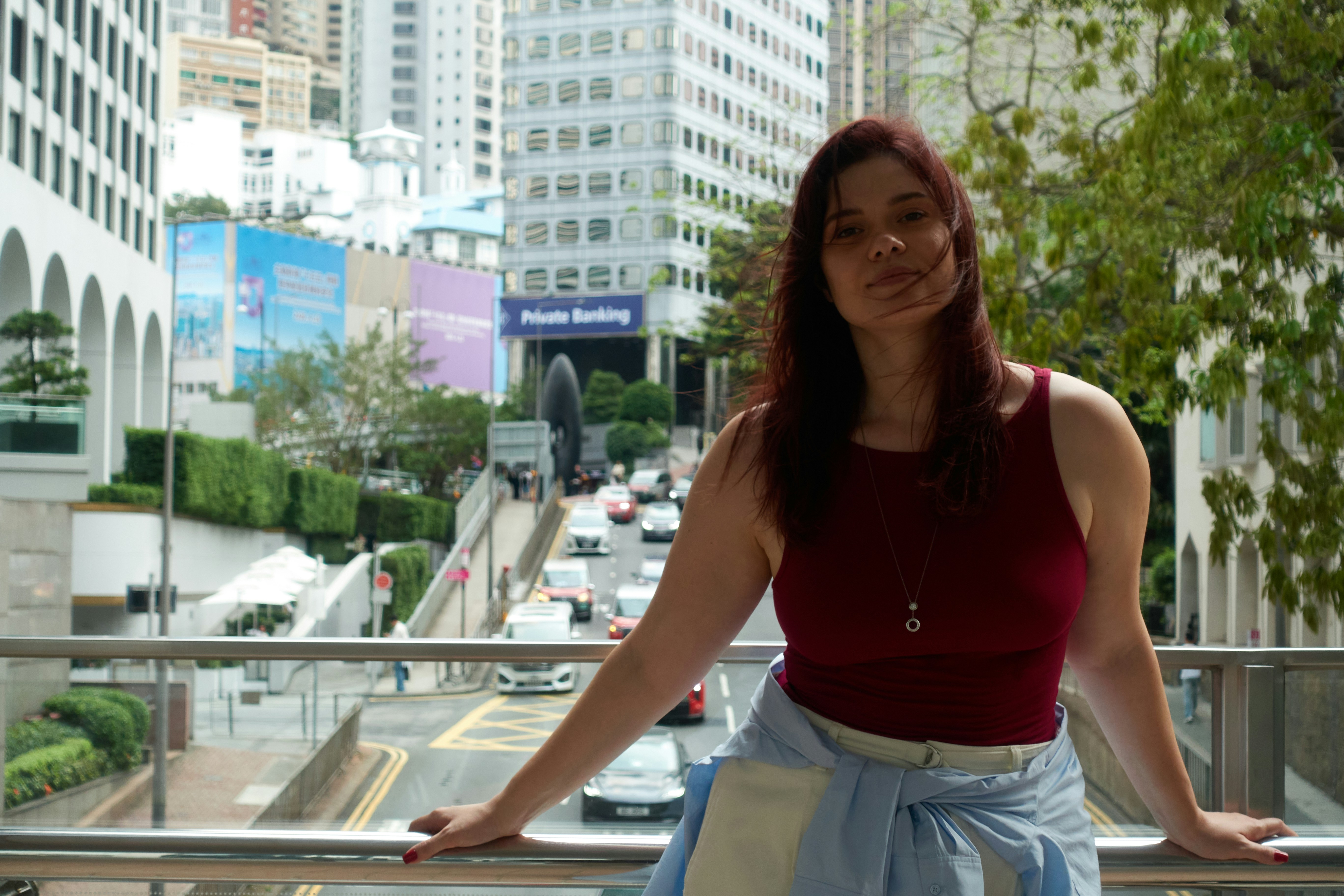 Mulher parada em uma ponte com prédios da cidade atrás dela