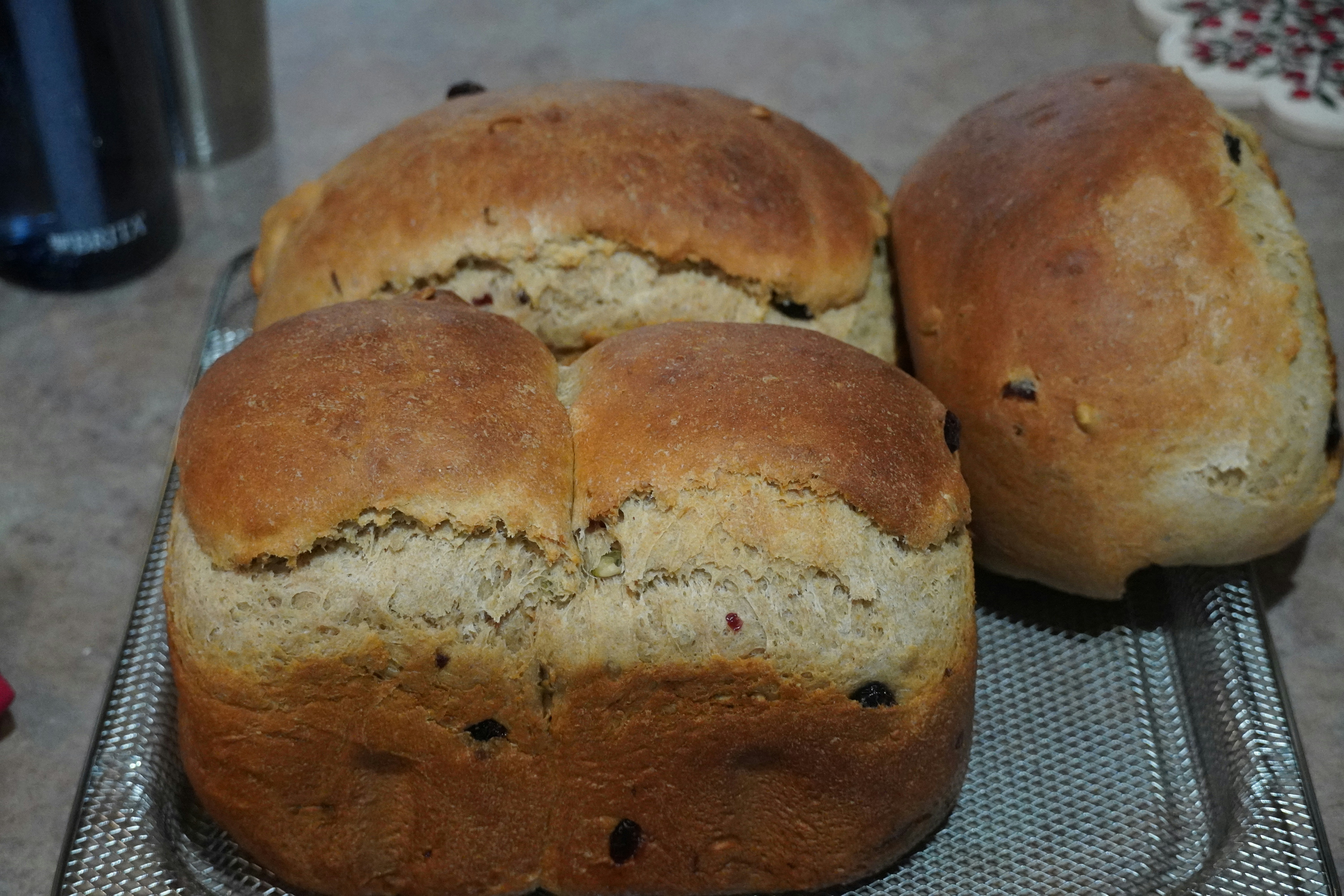 Three loaves of freshly baked bread on a cooling rack.