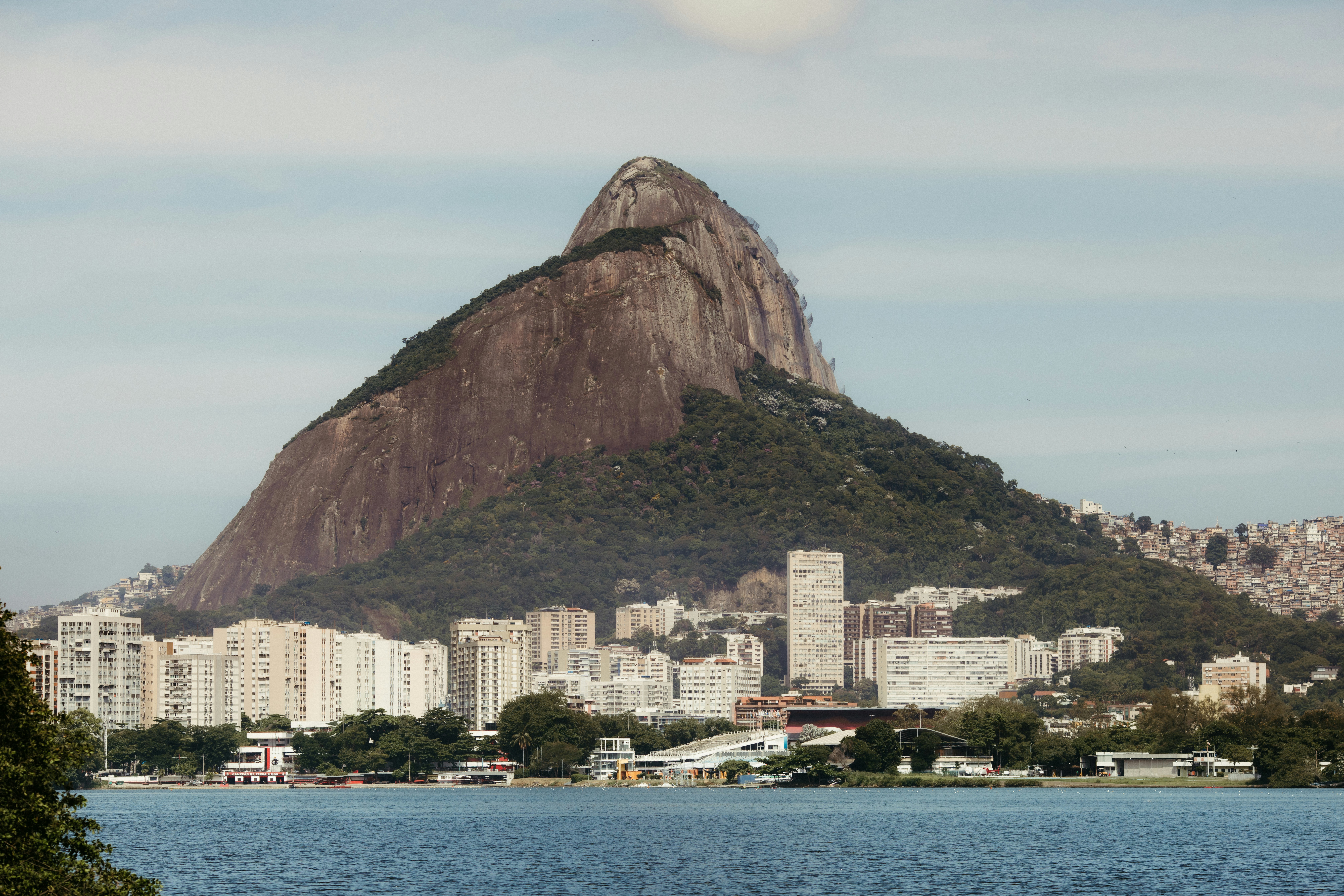 A large mountain overlooks a city by the water.