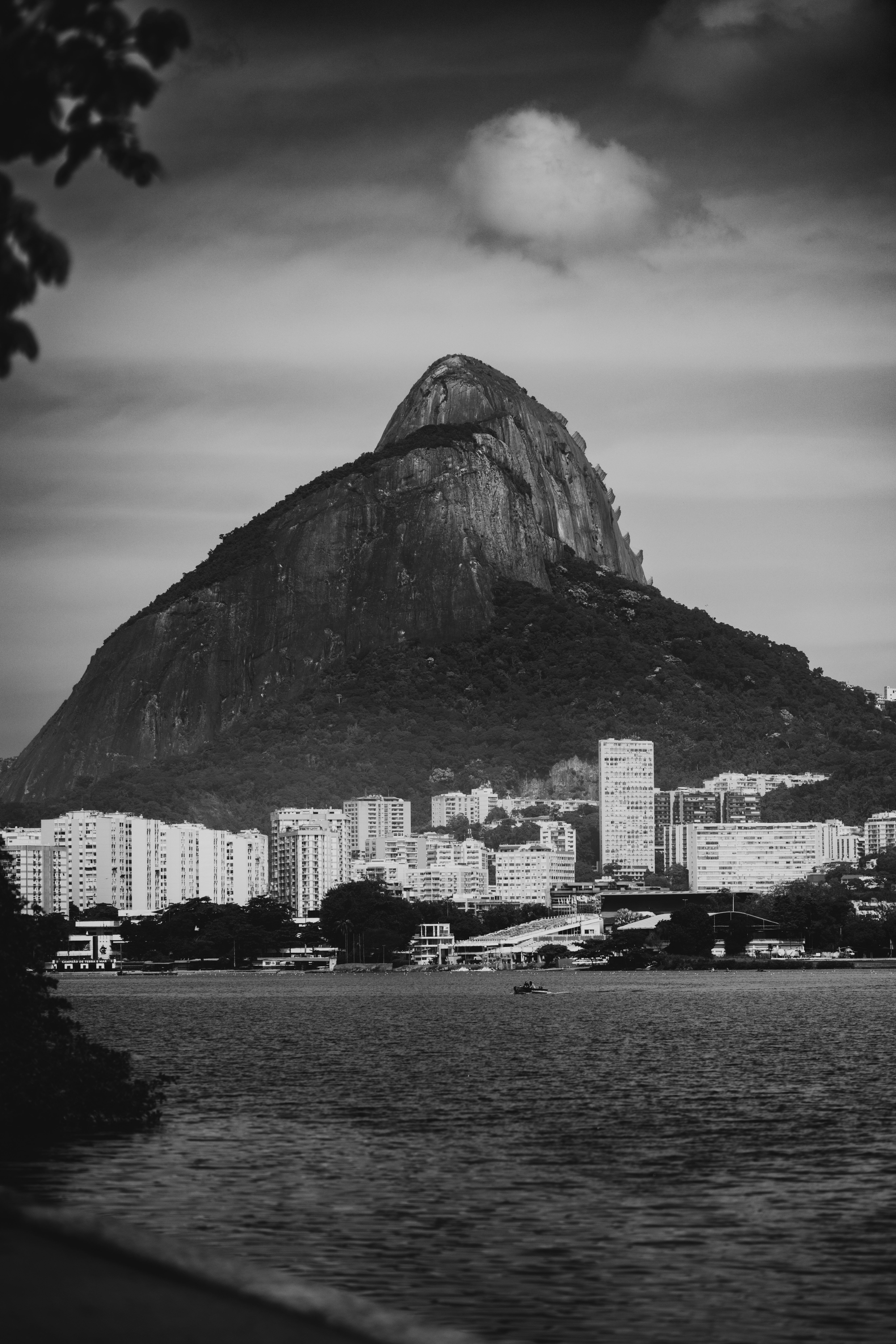 Mountain overlooks city buildings and a calm body of water.