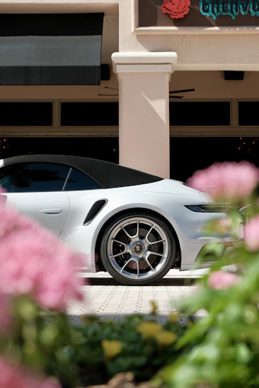 White convertible car parked outside building with flowers